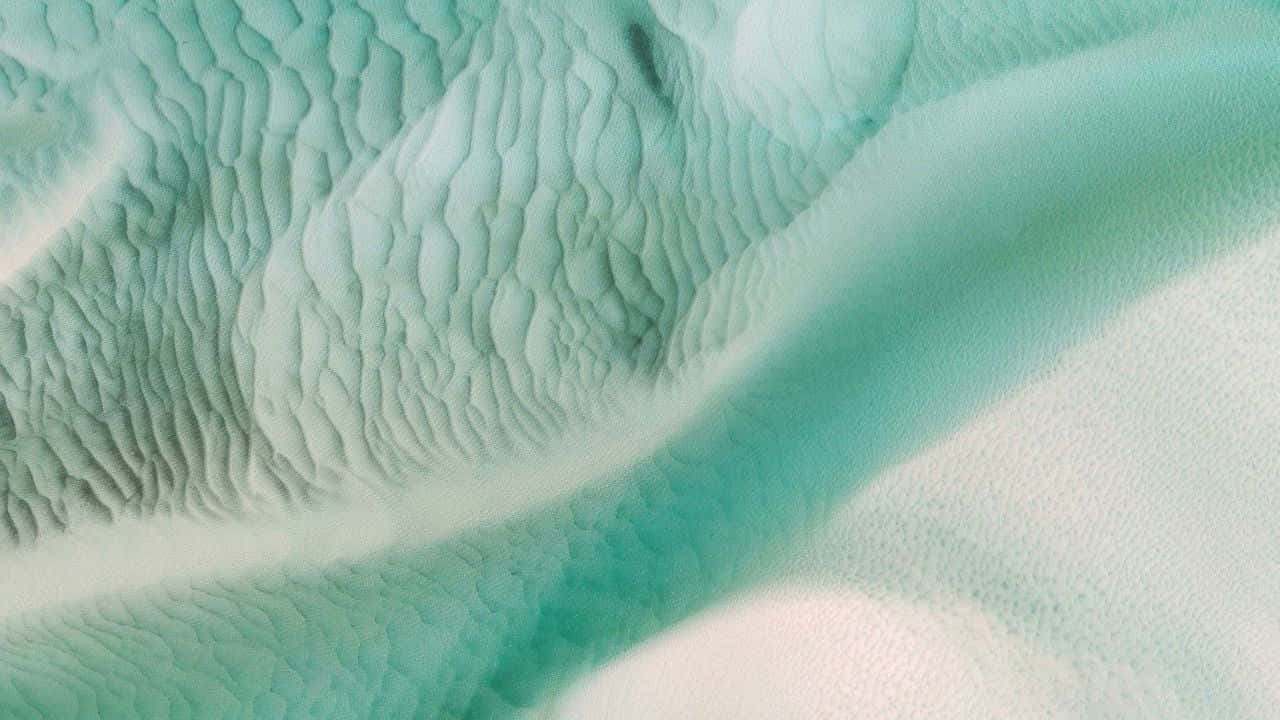 桌布 壁紙 — 柔軟青綠色和白色紋理布料的特寫，帶有流動波浪圖案和柔和陰影。