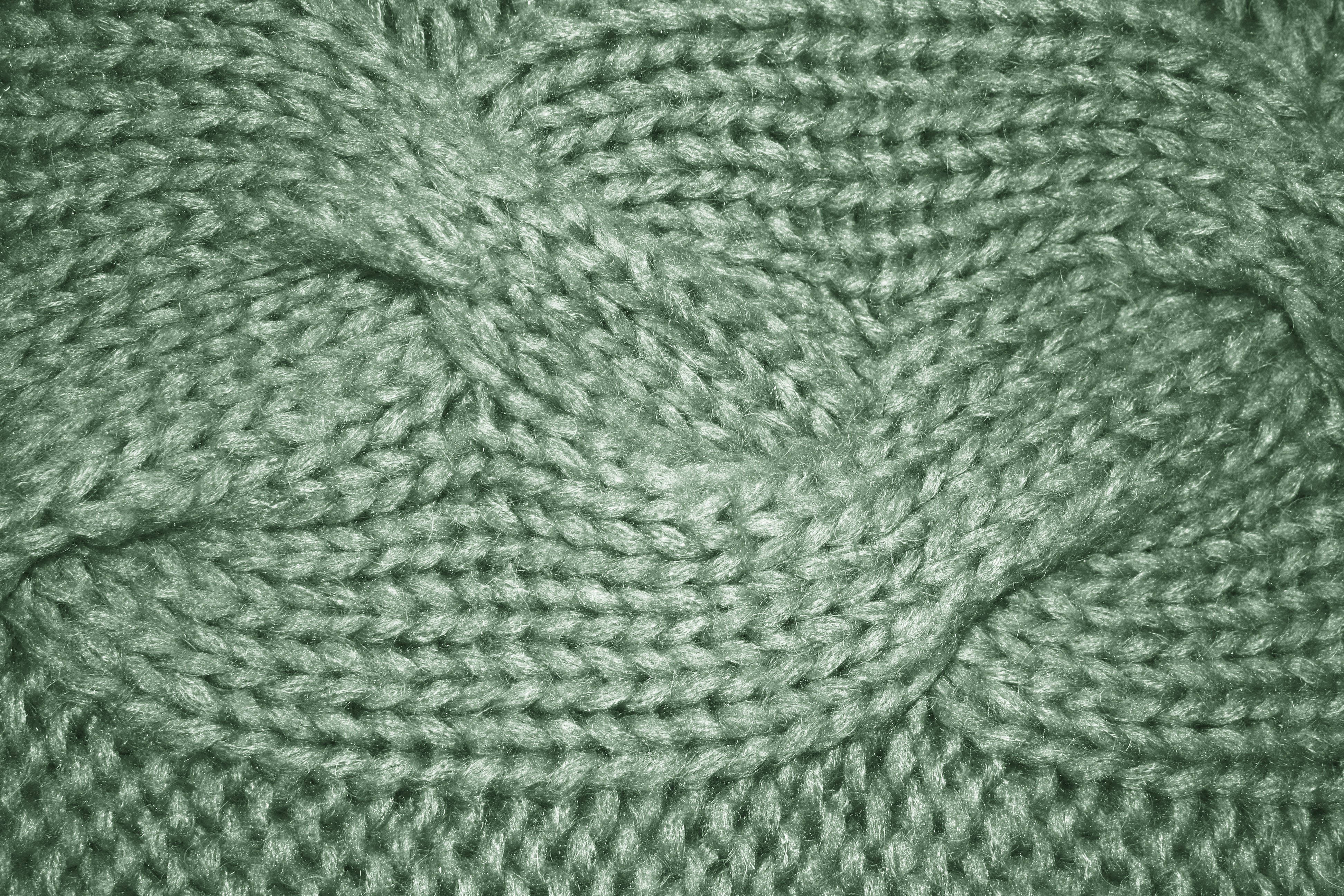 Sage 桌布 壁紙 — 柔軟鼠尾草綠色電纜針織布料的特寫，顯示出紋理針腳和舒適纖維。