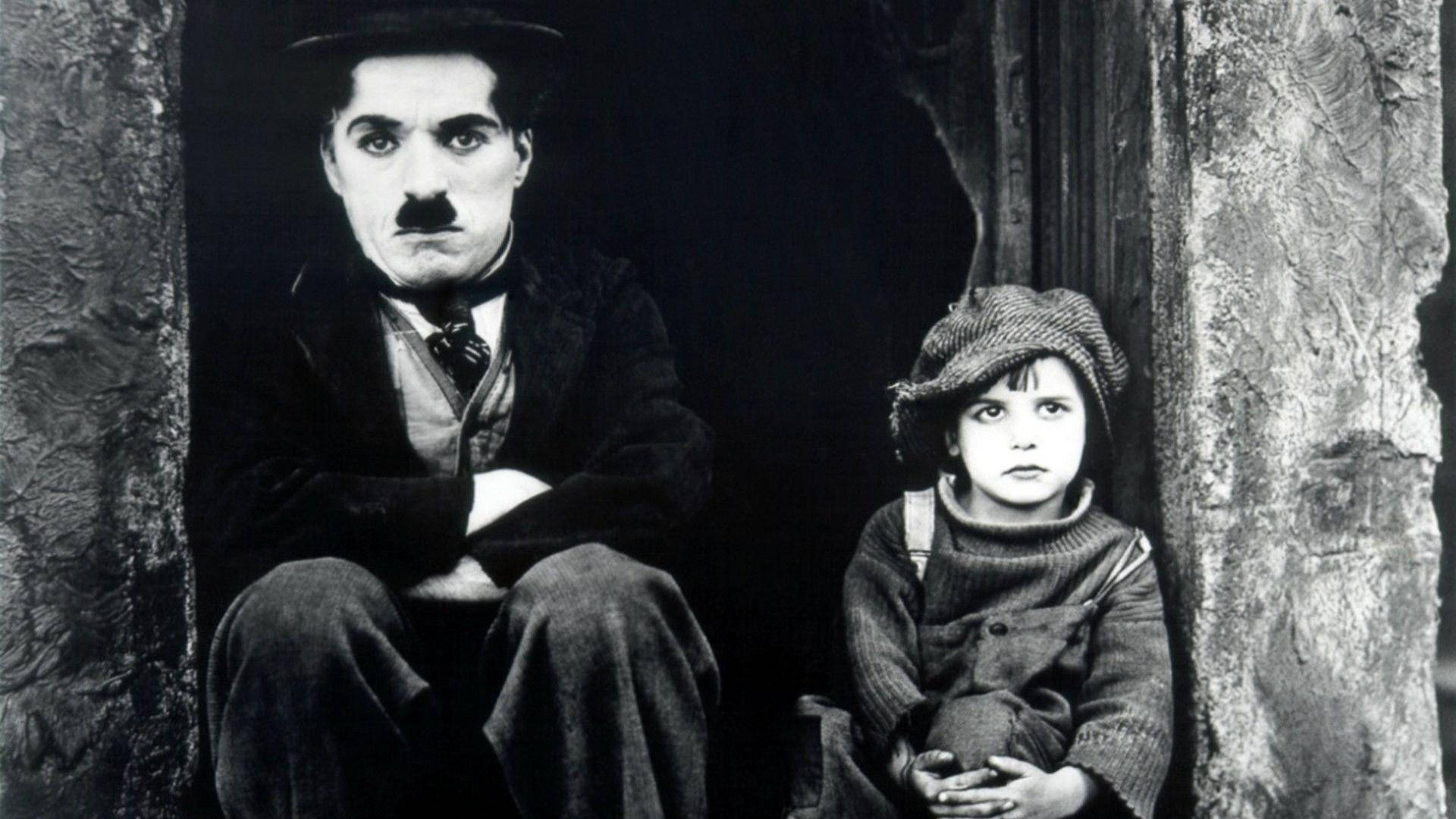 Chaplin 桌布 壁紙 — 查理·卓別林和一個孩子莊嚴地坐在有紋理的石柱之間的經典黑白電影片段。