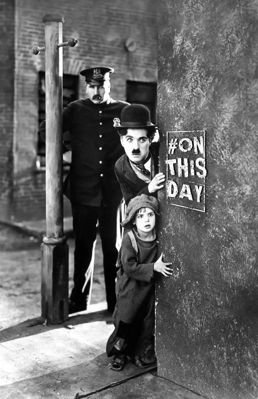 Chaplin 桌布 壁紙 — 查理·卓別林和一個孩子躲在牆後，附近站著一名警察的經典黑白場景。