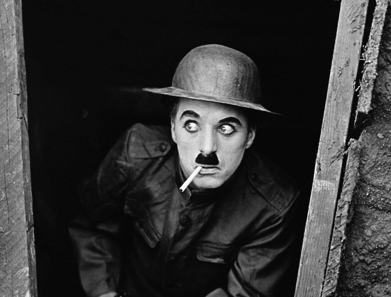 Chaplin 桌布 壁紙 — 查理·卓別林從木門後探出頭來，睜大眼睛，嘴裡叼著香煙，經典黑白肖像。