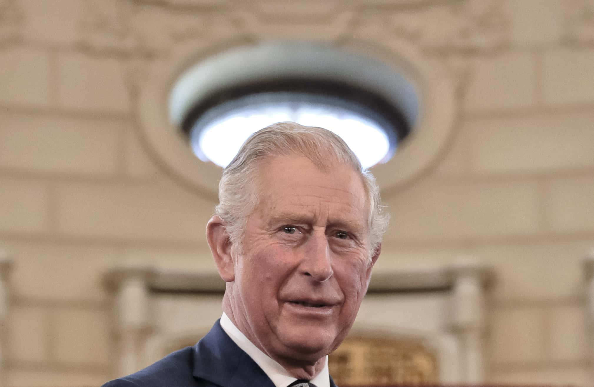Politics 桌布 壁紙 — 查理斯三世國王身穿正式西裝的特寫肖像，背景是柔和模糊的華麗石頭室內，上方有一個圓形天窗。