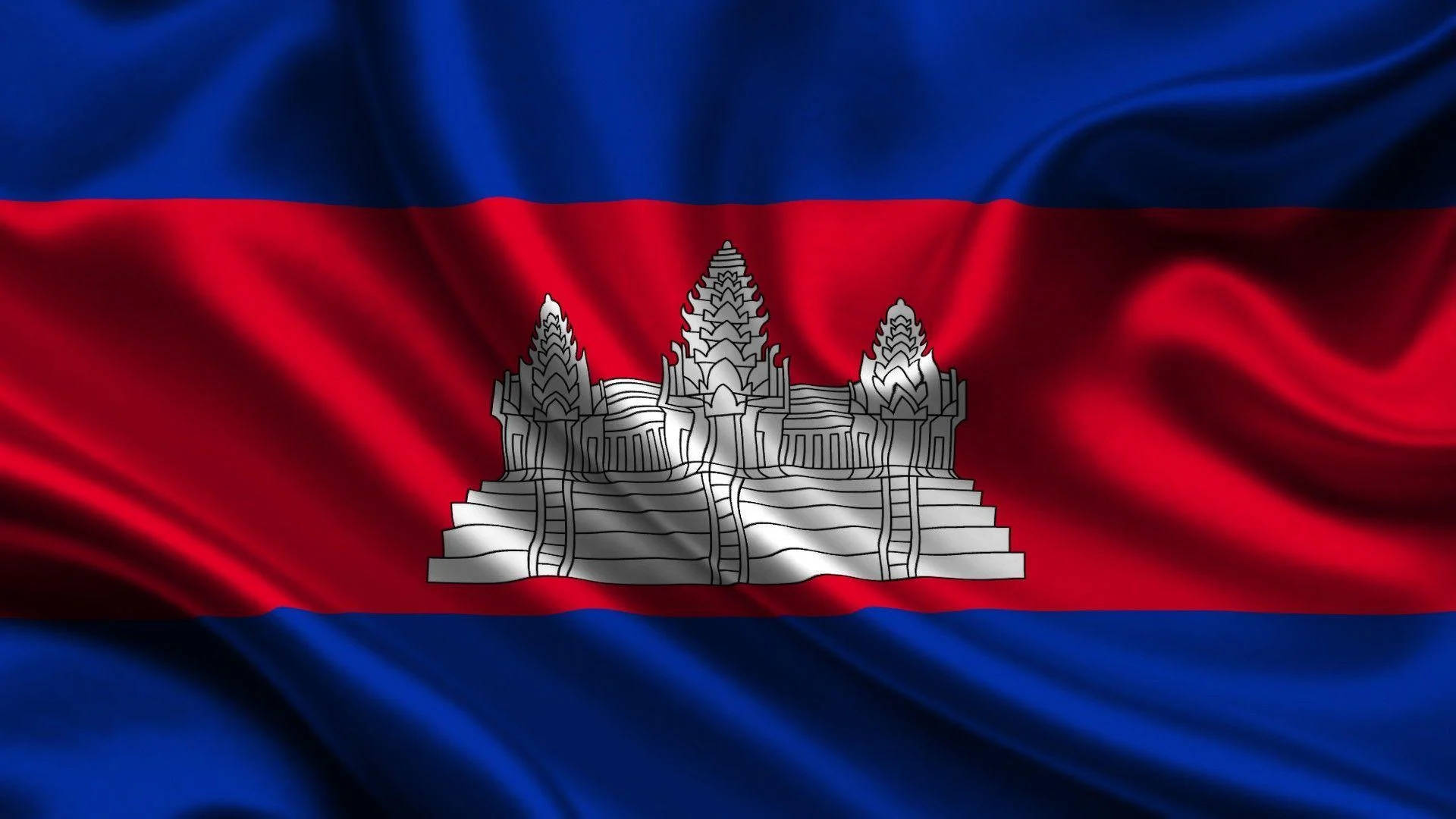 Flag 桌布 壁紙 — 柬埔寨國旗動態飄揚，帶有豐富的藍色、紅色和銀色色調，中央是標誌性的吳哥窟寺廟。