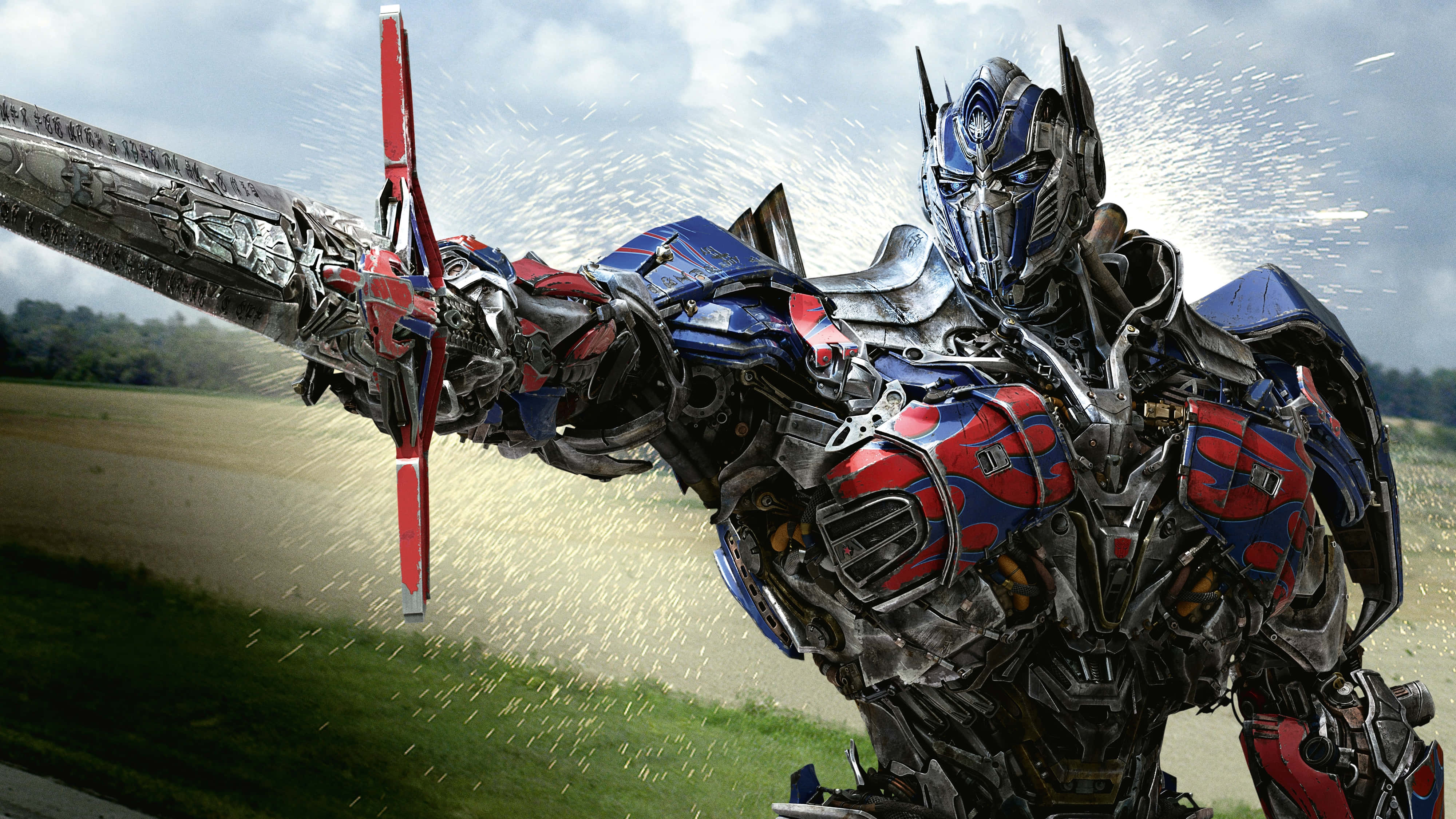 Optimus Prime 4K 桌布 壁紙 — 柯博文以戰鬥姿態，在飛揚的碎片和陰雲密佈的天空中揮舞著發光的劍。