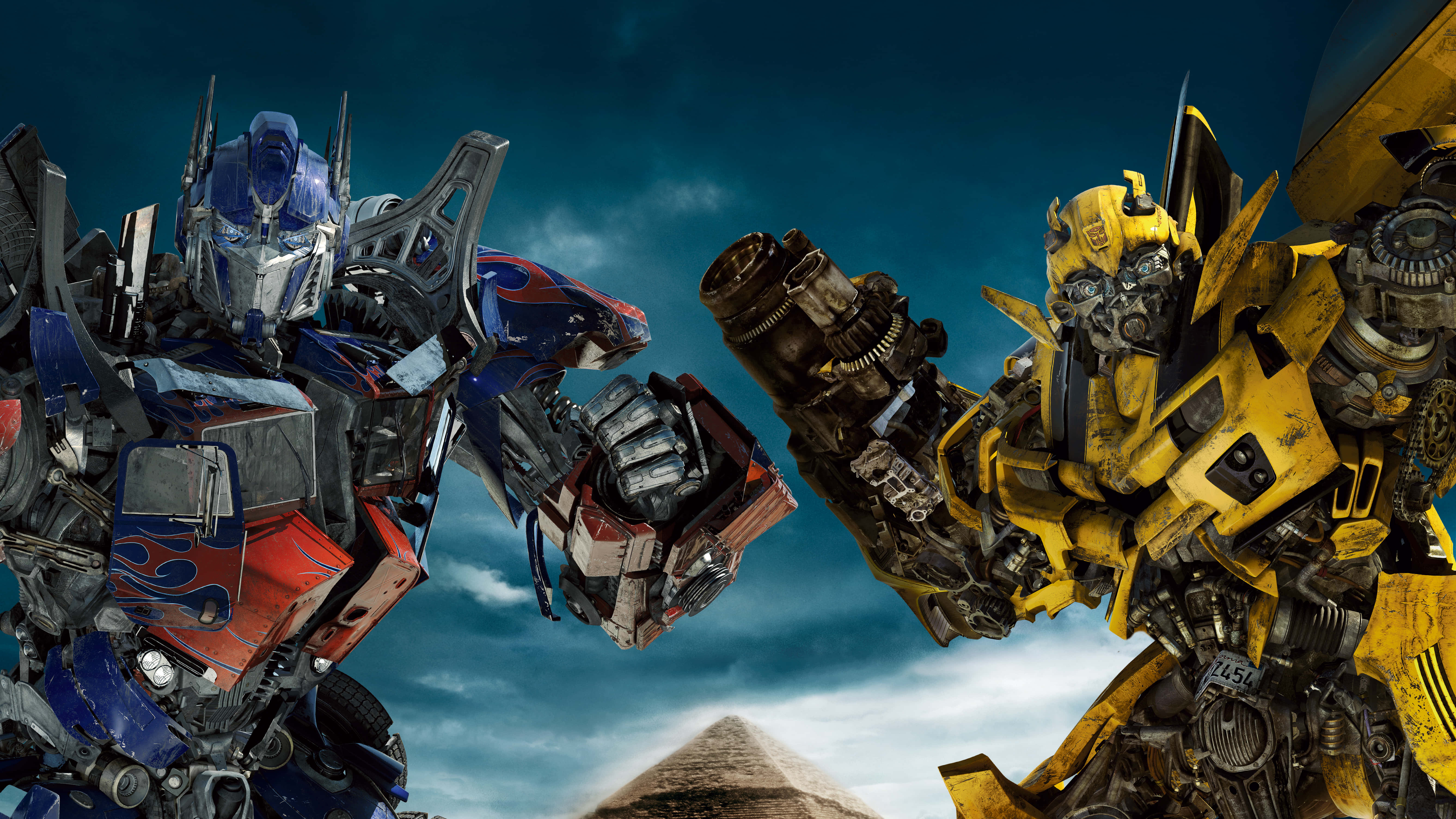 Optimus Prime 4K 桌布 壁紙 — 柯博文與大黃蜂在戲劇性的天空下對峙，下方有一座金字塔。
