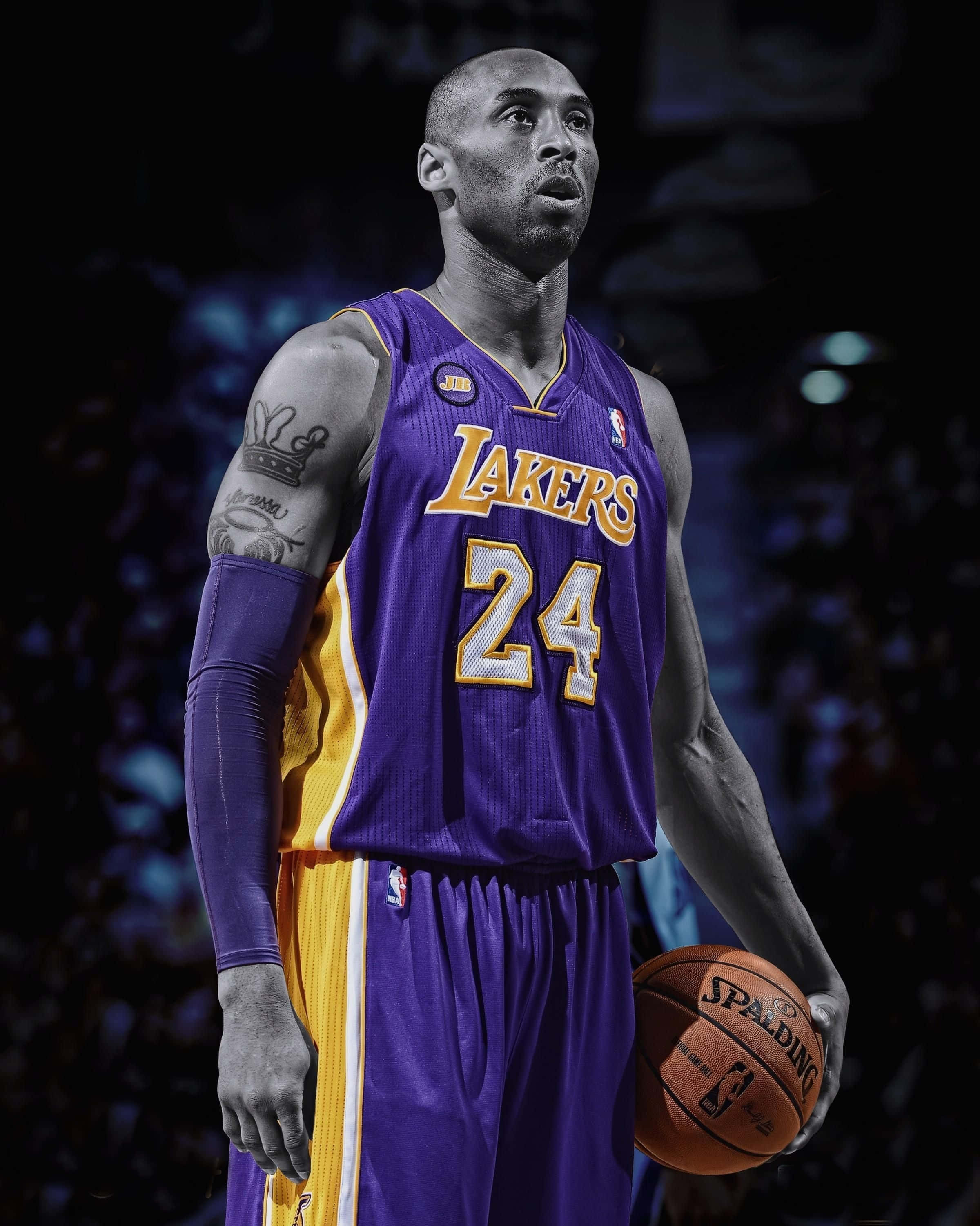 Kobe Bryant Basketball 桌布 壁紙 — 柯比·布萊恩穿著紫色和金色的湖人隊球衣，在黑暗的球場背景下，專注地拿著籃球。