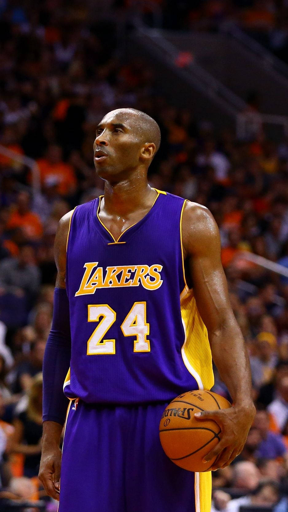 NBA iPhone 桌布 壁紙 — 柯比·布萊恩身穿湖人隊24號球衣，在場館燈光下專注地持球比賽。