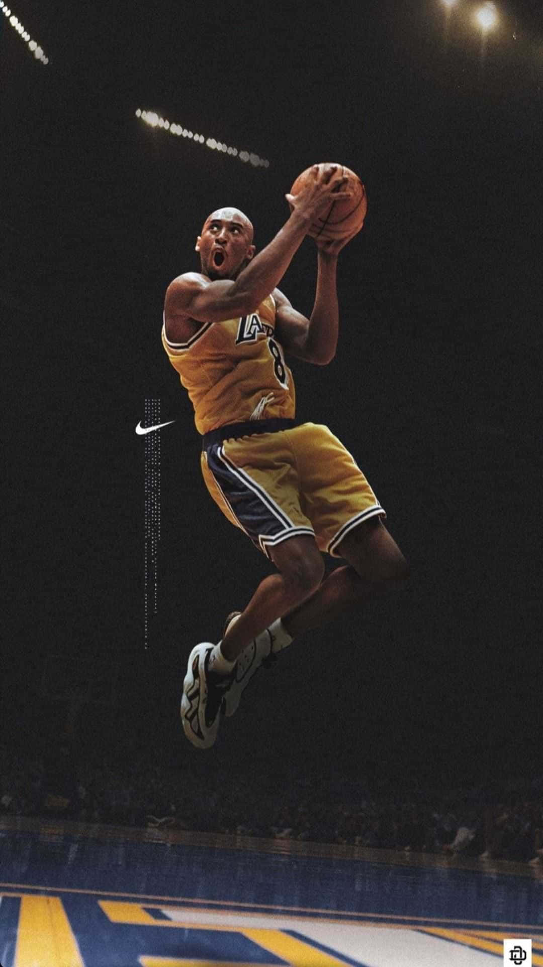 Kobe Basketball 桌布 壁紙 — 柯比·布萊恩身穿黃色湖人隊球衣，在明亮的場館燈光下，手抱籃球在空中飛翔。
