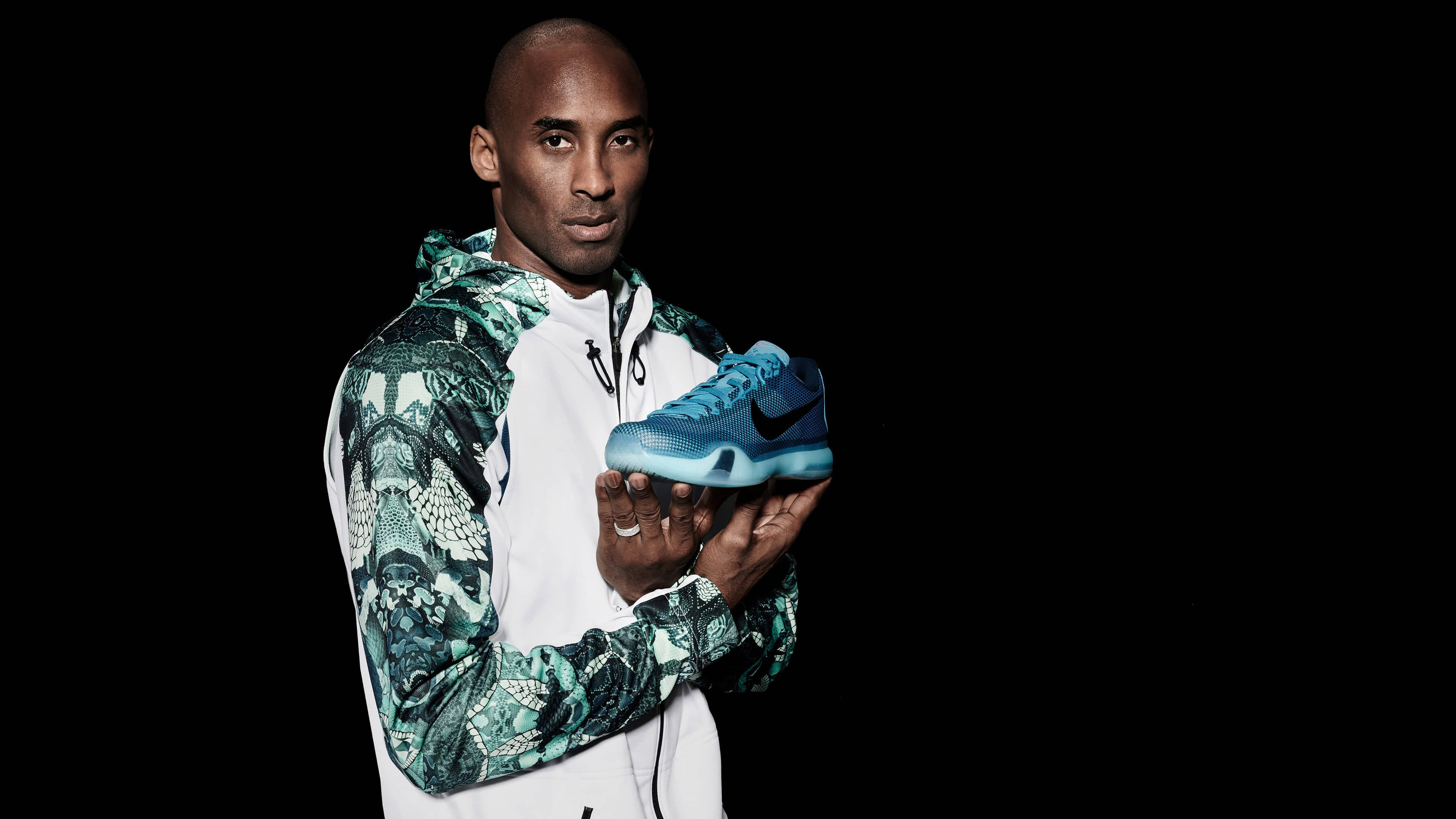 籃球 桌布 壁紙 — 柯比布萊恩在工作室肖像中，手持一雙藍色Nike運動鞋，背景為純黑色。