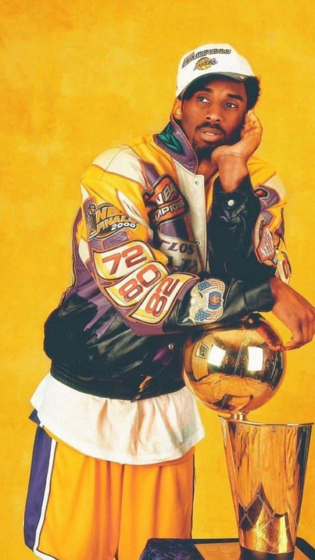 Kobe Basketball 桌布 壁紙 — 柯比布萊恩身穿湖人冠軍裝備，在溫暖的黃色背景下，若有所思地站在NBA總決賽獎盃旁邊。