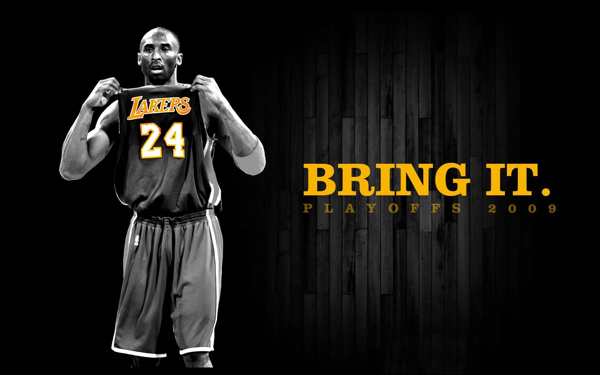 Kobe Basketball 桌布 壁紙 — 柯比布萊恩身穿湖人球衣，在深色木質背景前舉起他的24號球衣，並有粗體黃色文字寫著「BRING IT。」