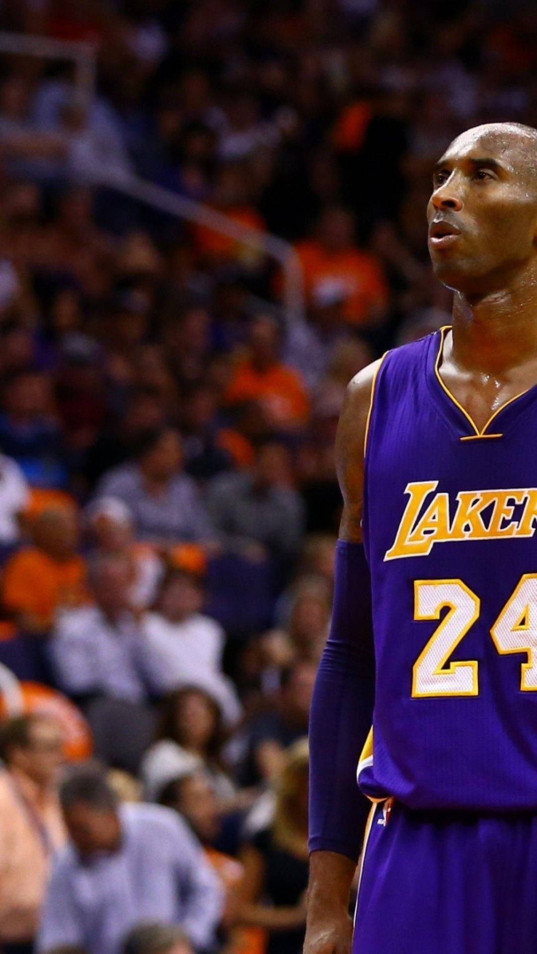 Kobe Bryant iPhone 桌布 壁紙 — 柯比布萊恩身穿紫色湖人隊24號球衣，在模糊的人群背景下專注地站立於籃球比賽中。
