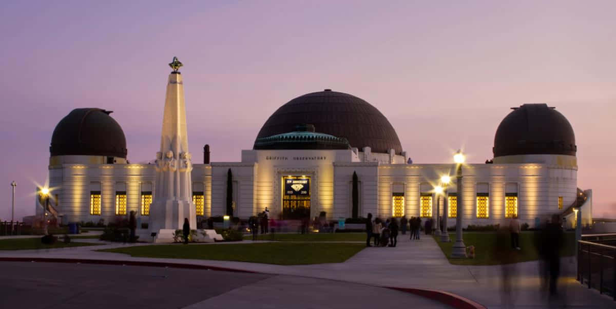 Observatory 桌布 壁紙 — 格里菲斯天文台在黃昏時亮起溫暖燈光，映襯著紫色天空和剪影般的遊客。