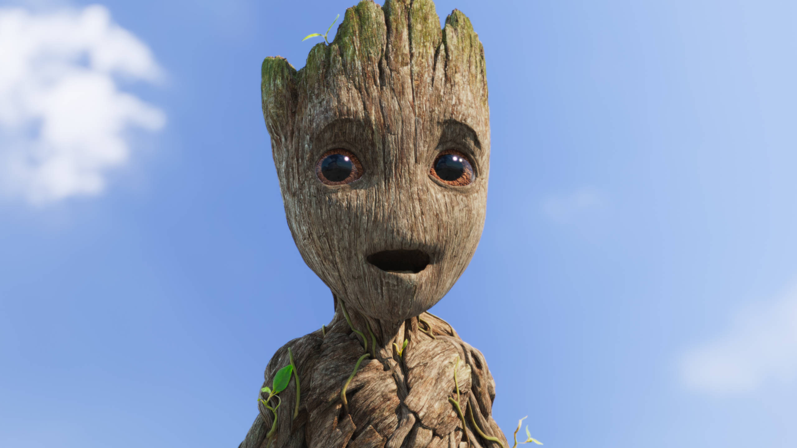 Baby Groot 桌布 壁紙 — 格魯特表情豐富的臉部特寫，背景是清澈的藍天和柔軟的白雲。