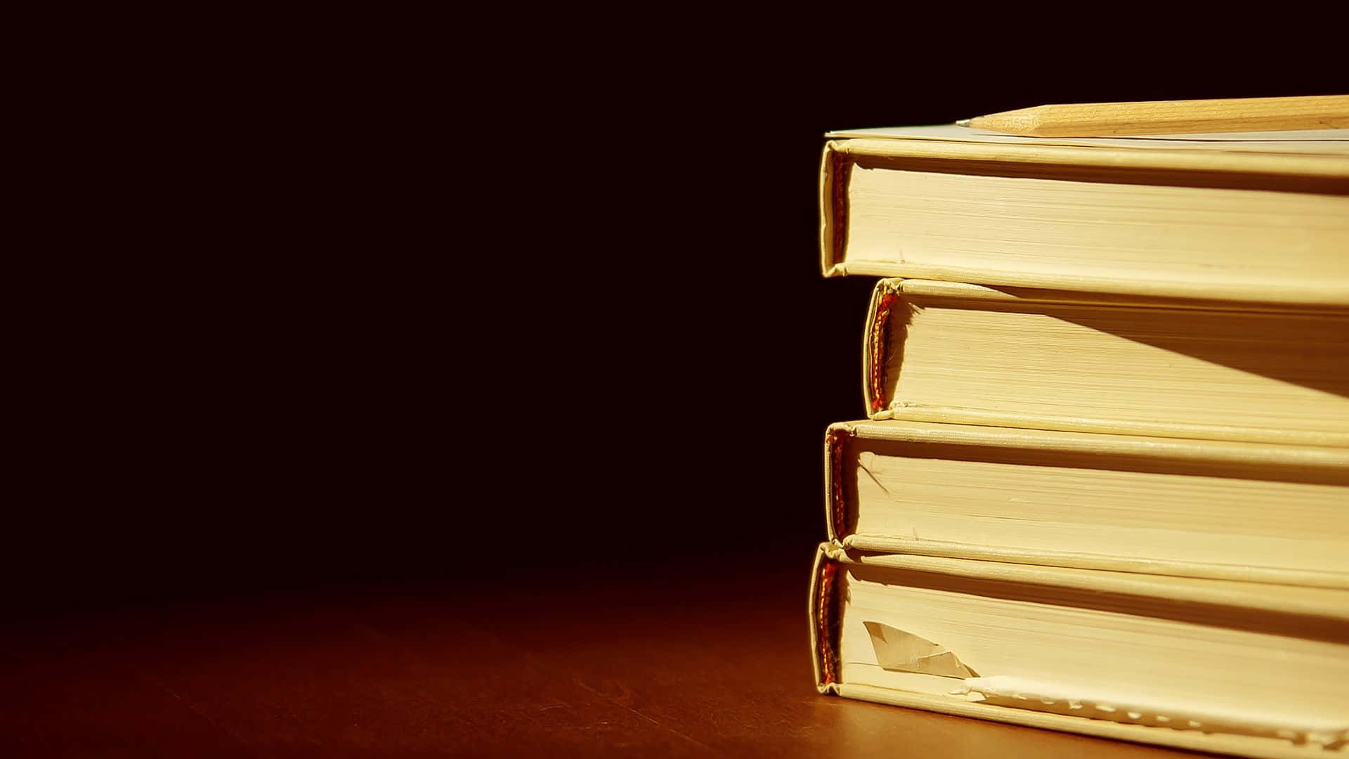 桌上的一疊書，背後有光 壁紙