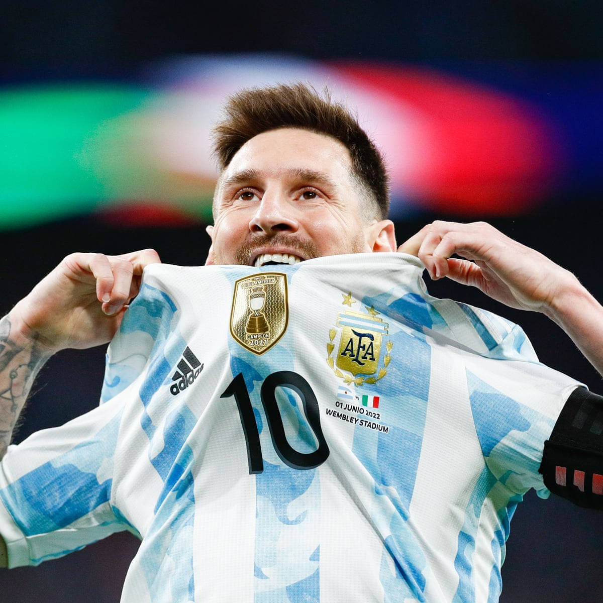Argentina National Football Team 桌布 壁紙 — 梅西在溫布利球場高舉帶有2022年世界盃臂章的阿根廷球衣，露出勝利的笑容。