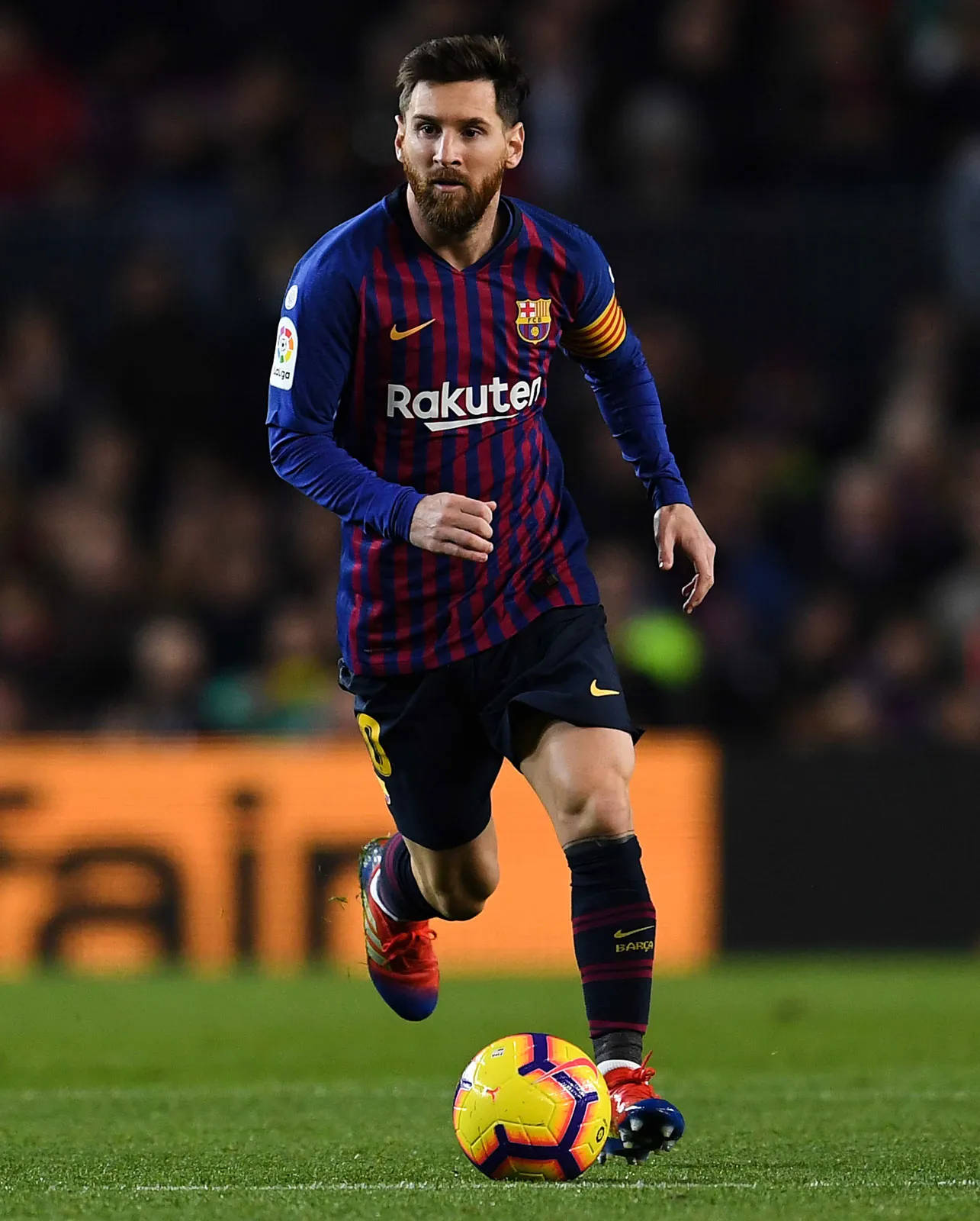 Messi 4K Ultra HD 桌布 壁紙 — 梅西在球場燈光下的綠色草地上盤球，背景有模糊的球迷。