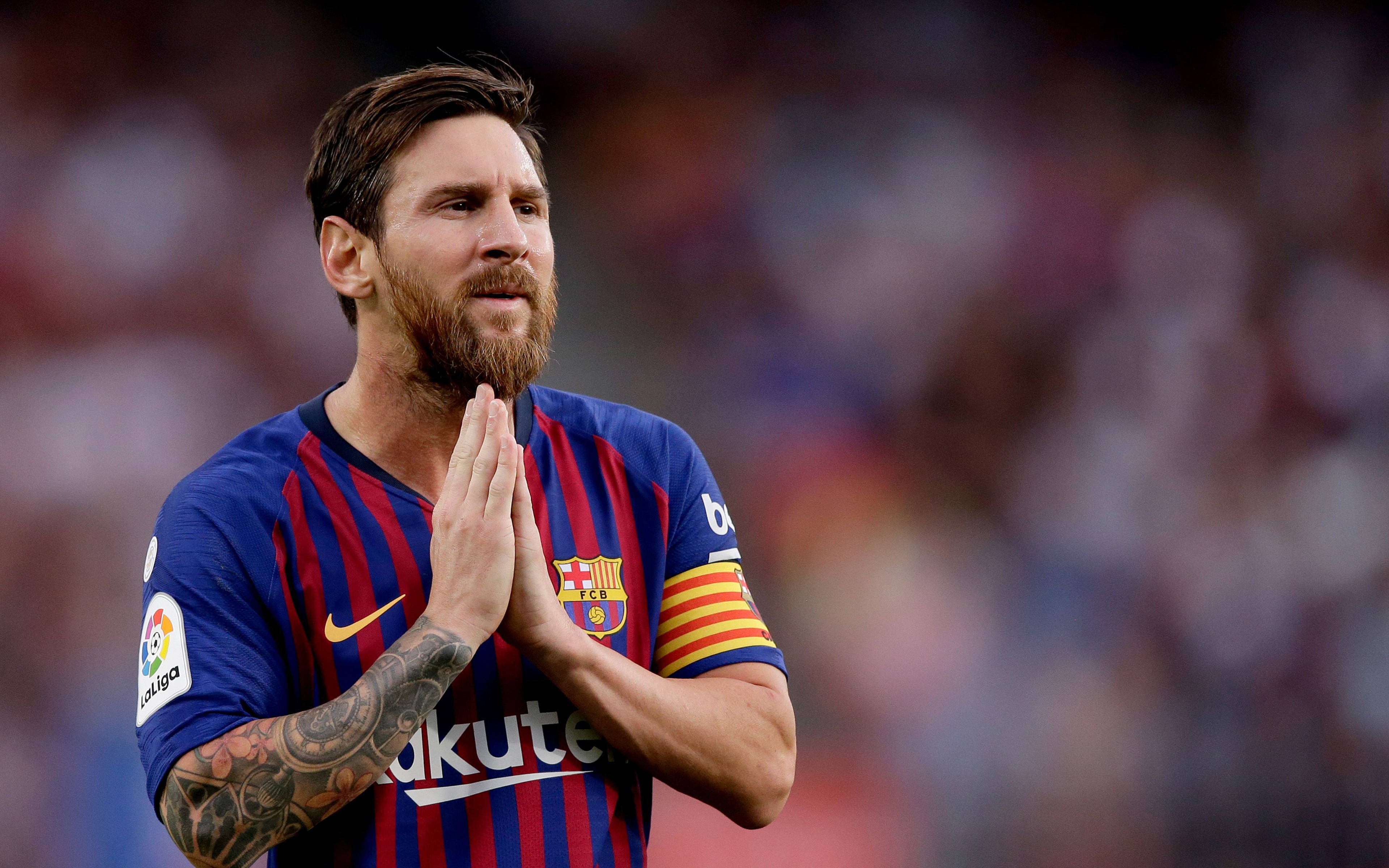 Messi 4K Ultra HD 桌布 壁紙 — 梅西身穿藍紅間條巴塞隆納球衣，在模糊的球場觀眾面前合十雙手表示感謝。