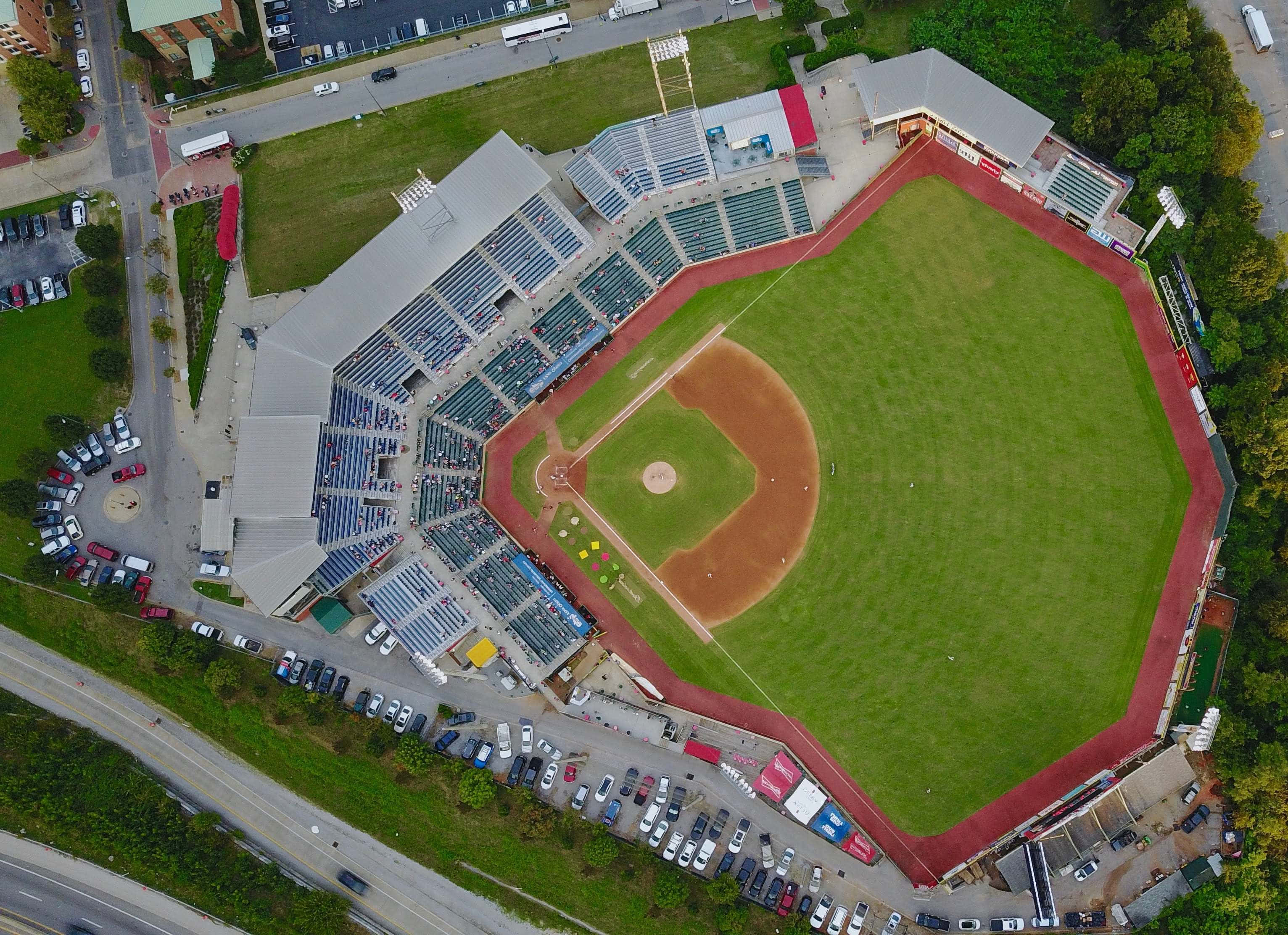 Baseball Field 桌布 壁紙 — 棒球場的鳥瞰圖，有綠色場地、棕色泥土內野和周圍停滿汽車的停車場。