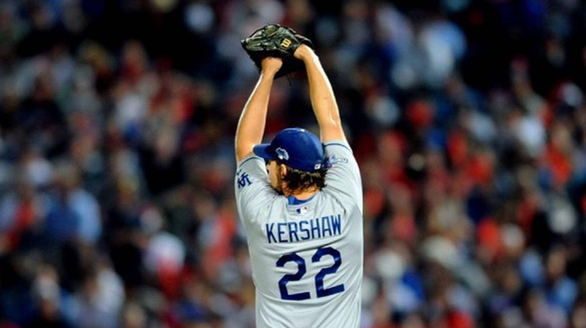 洛杉磯道奇隊 桌布 壁紙 — 棒球投手Kershaw 22號在夜間模糊的體育場人群上方高舉手套慶祝勝利。