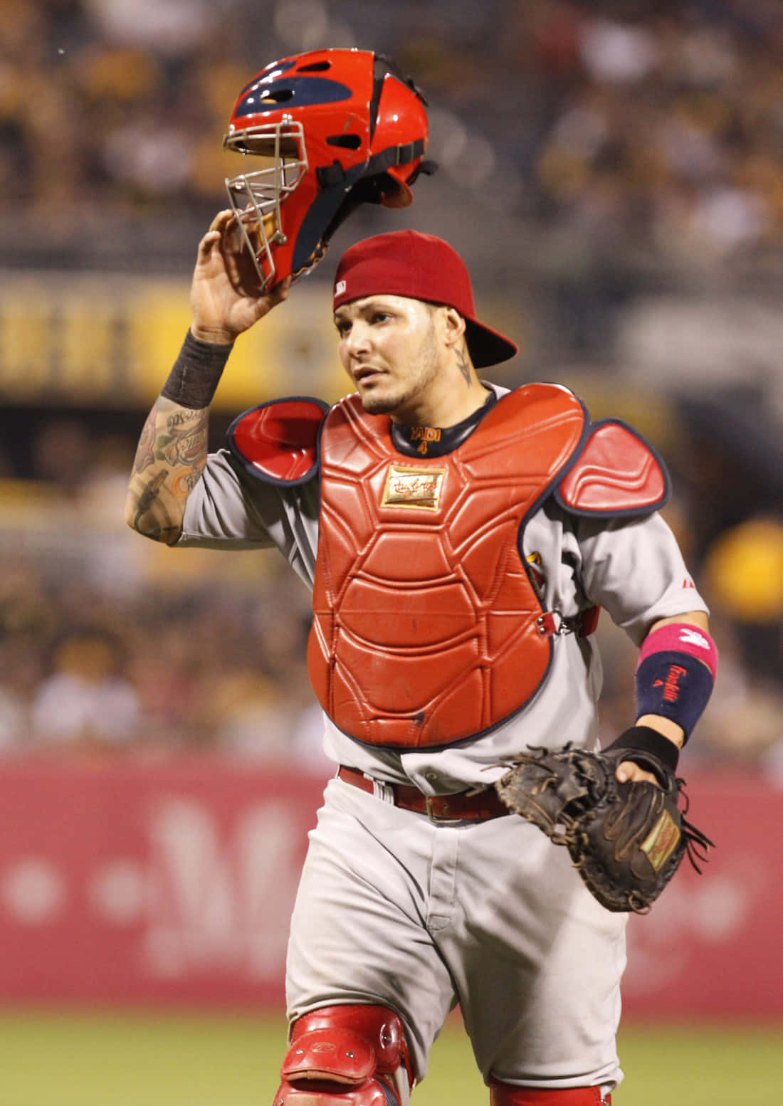 Yadier Molina 桌布 壁紙 — 棒球捕手身穿紅色裝備，在球場燈光下向人群傾斜頭盔。