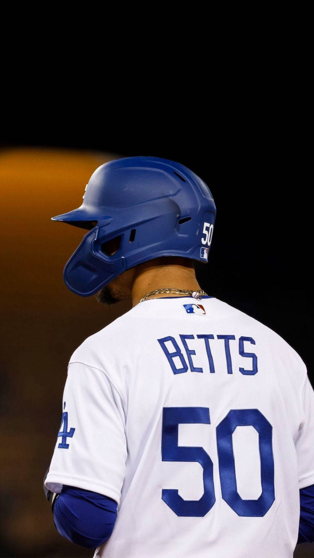 Mookie Betts 桌布 壁紙 — 棒球運動員貝茨身穿藍色頭盔和白色球衣，背號50，在球場燈光下的背影。