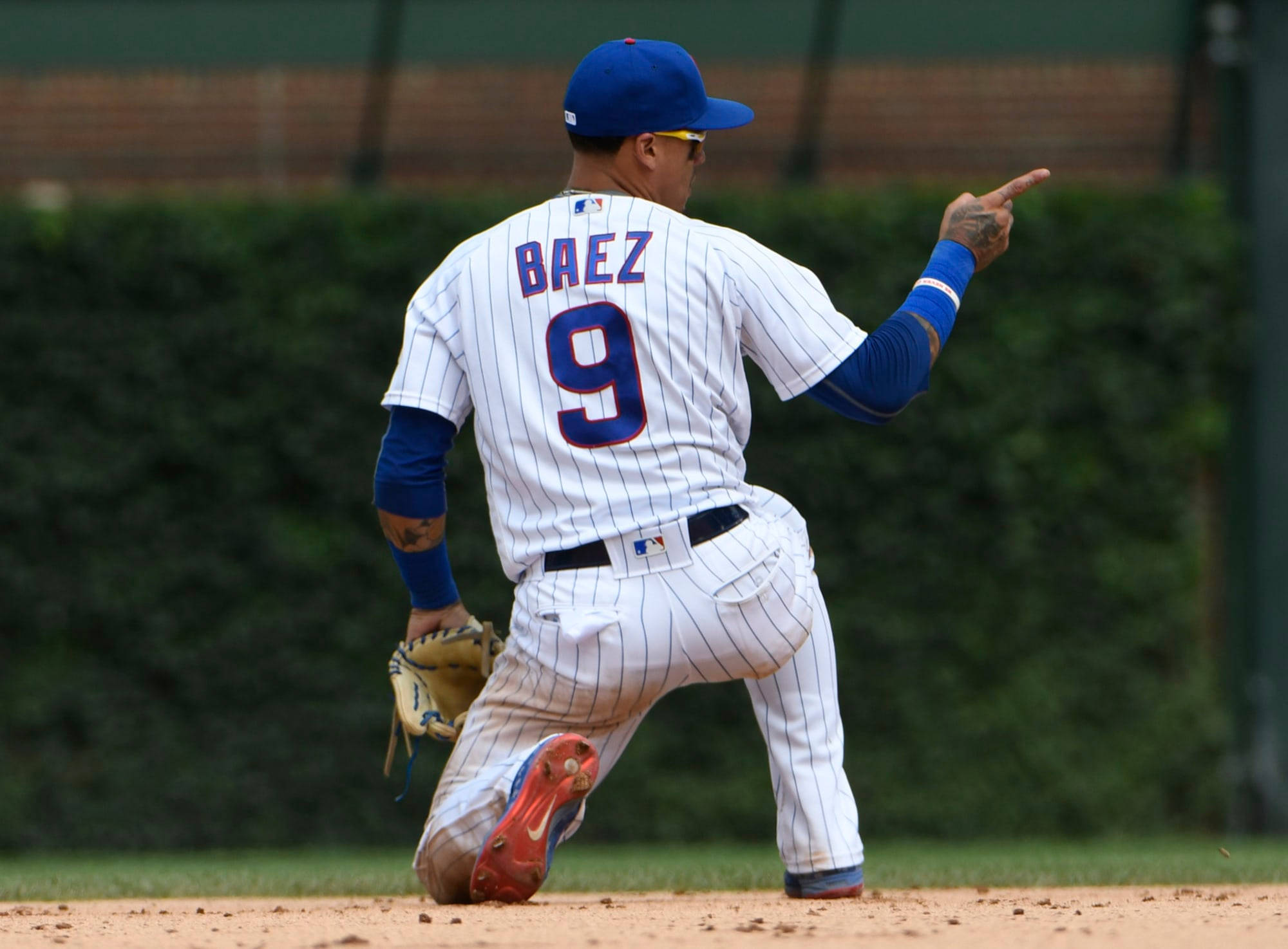 Baez 桌布 壁紙 — 棒球選手 Javier Baez 身穿白色細條紋制服，9號在陽光明媚的球場上向前指。