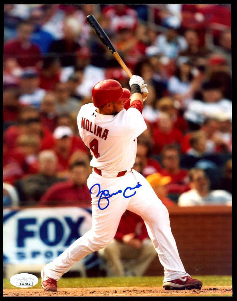 Yadier Molina 桌布 壁紙 — 棒球選手Molina身穿白色球衣在球場中揮棒，身後有模糊的人群。