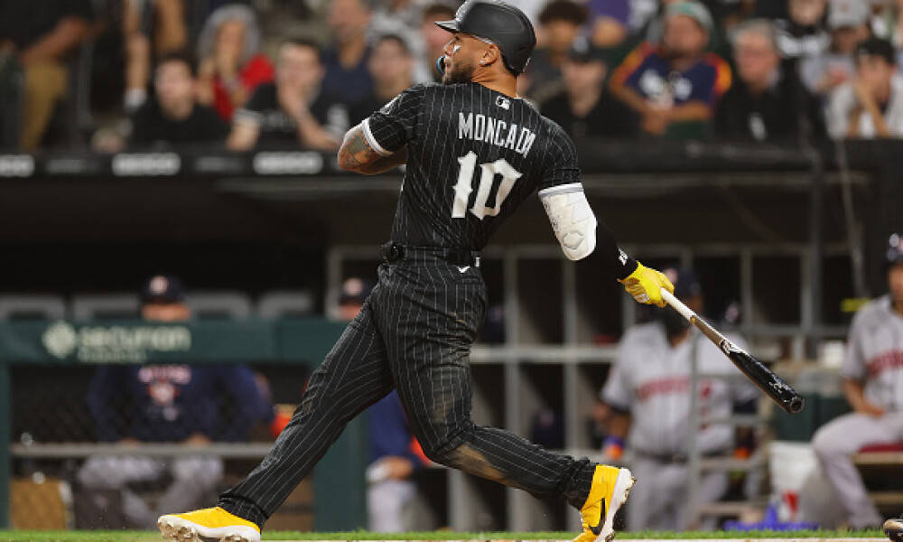 Athletic 桌布 壁紙 — 棒球選手Moncada身穿黑色細條紋球衣，在夜間比賽中揮棒，背景有觀眾。