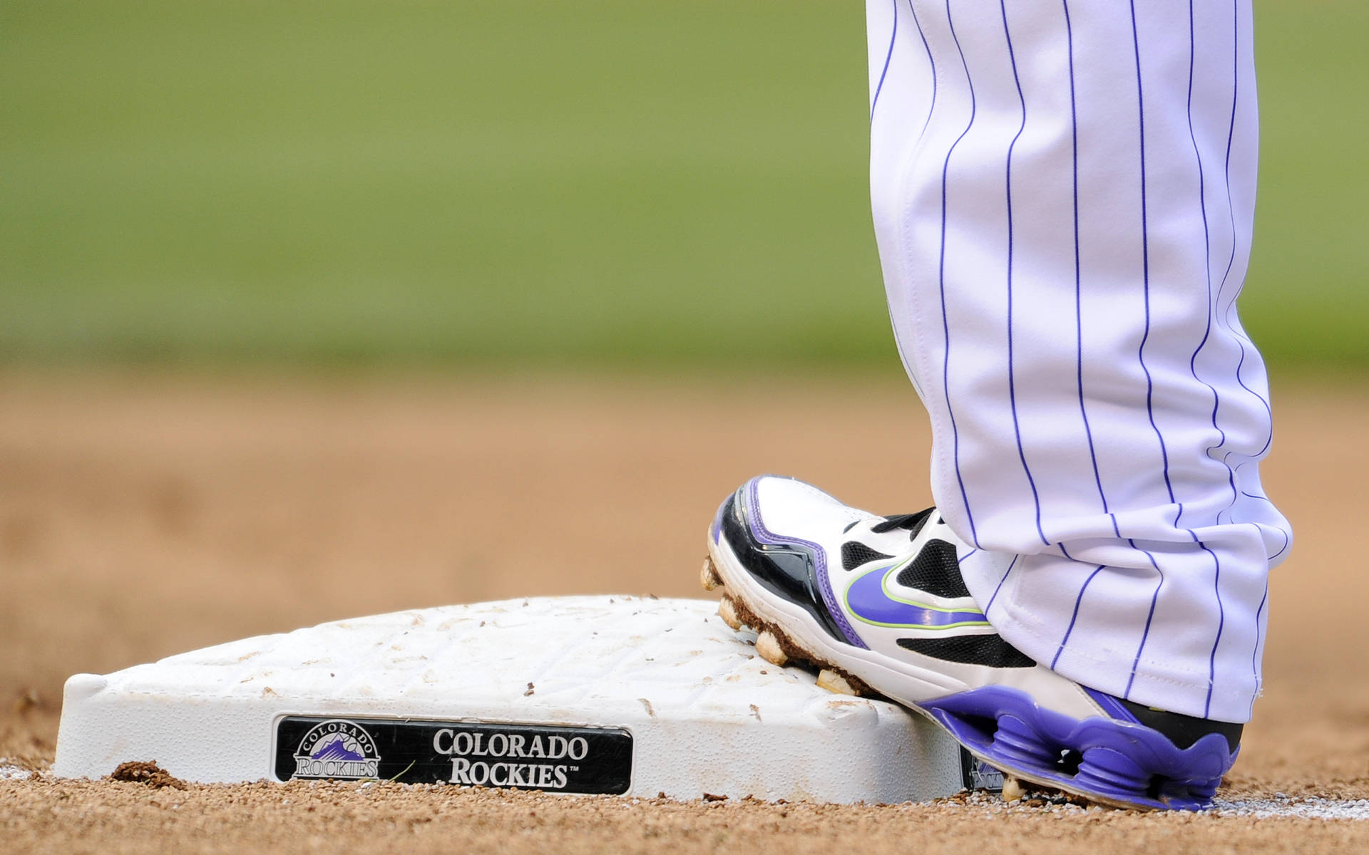 Rockies 桌布 壁紙 — 棒球選手穿著紫色和白色釘鞋的腳部特寫，穩固地踩在科羅拉多洛磯隊的壘包上。