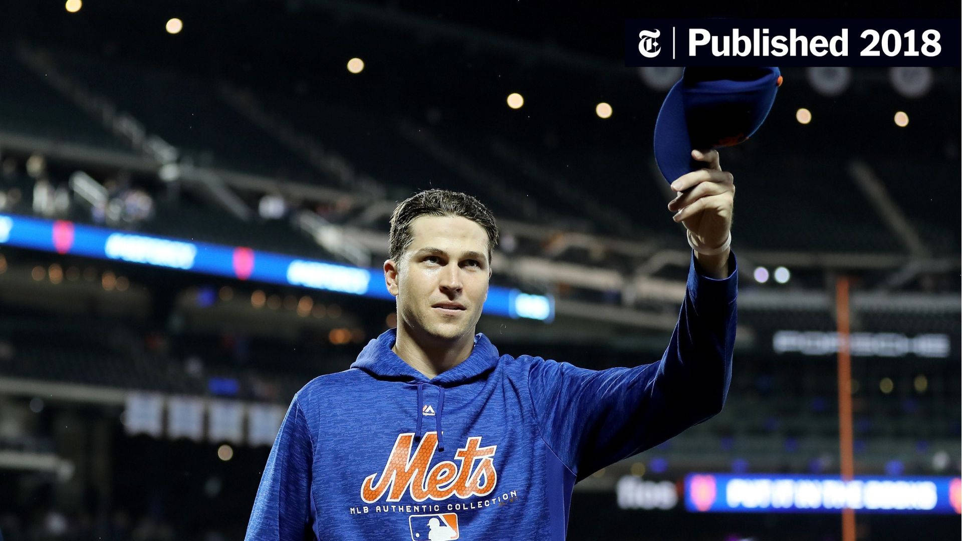 Degrom 桌布 壁紙 — 棒球選手身穿藍色Mets連帽衫，在夜晚的球場燈光下向人群脫帽致意。