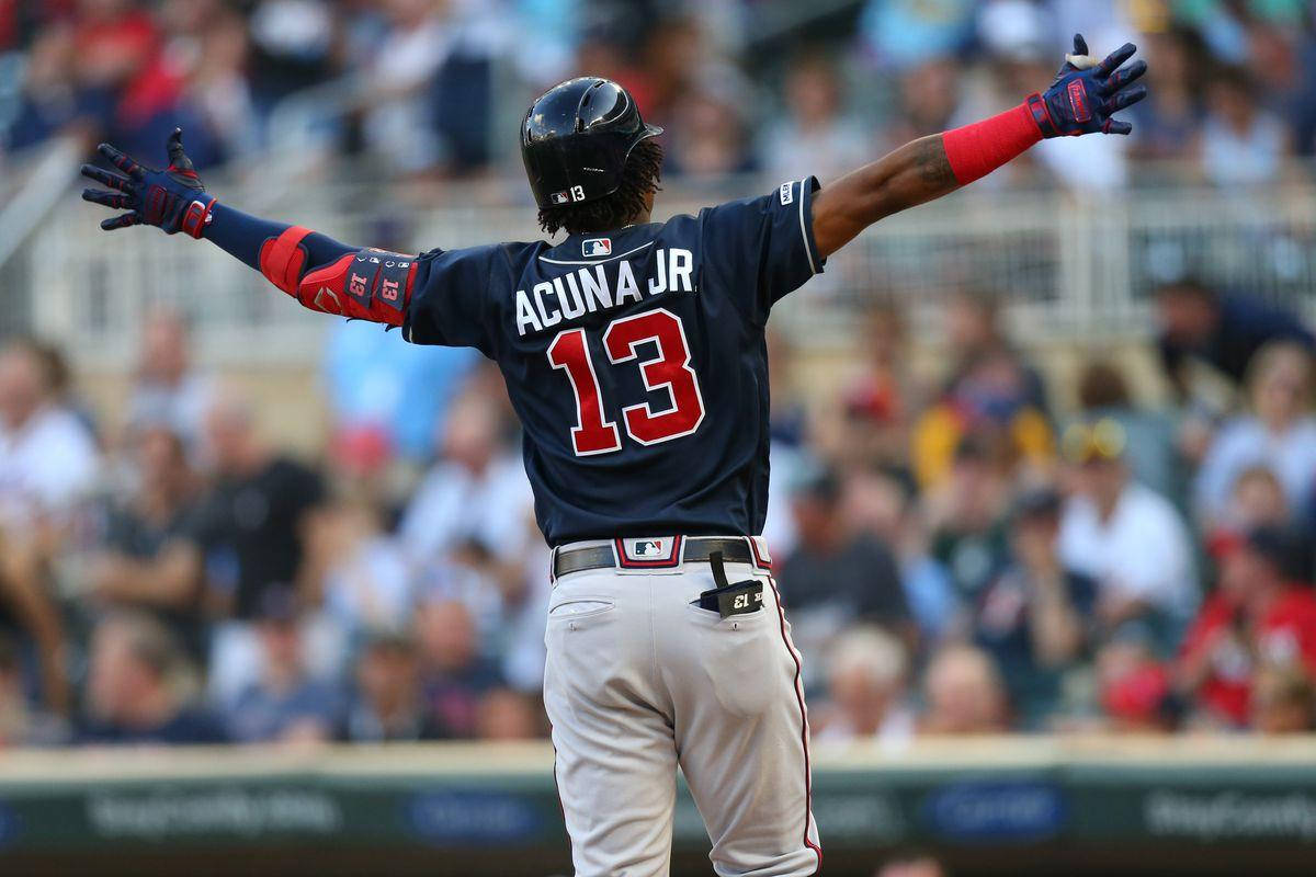 Acuna 桌布 壁紙 — 棒球選手阿庫尼亞 Jr. 在陽光明媚的球場上張開雙臂慶祝，背景中球迷歡呼。