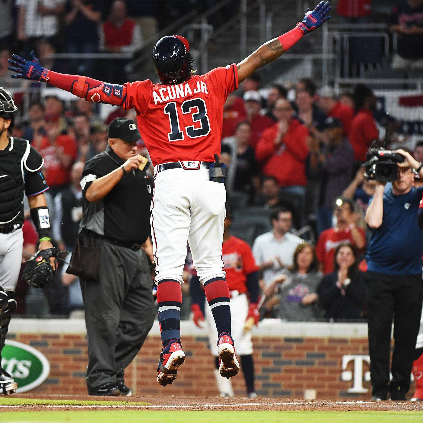 Acuna 桌布 壁紙 — 棒球選手阿庫尼亞 Jr. 身穿紅色13號球衣，在夜間比賽中歡欣跳躍，觀眾歡呼。