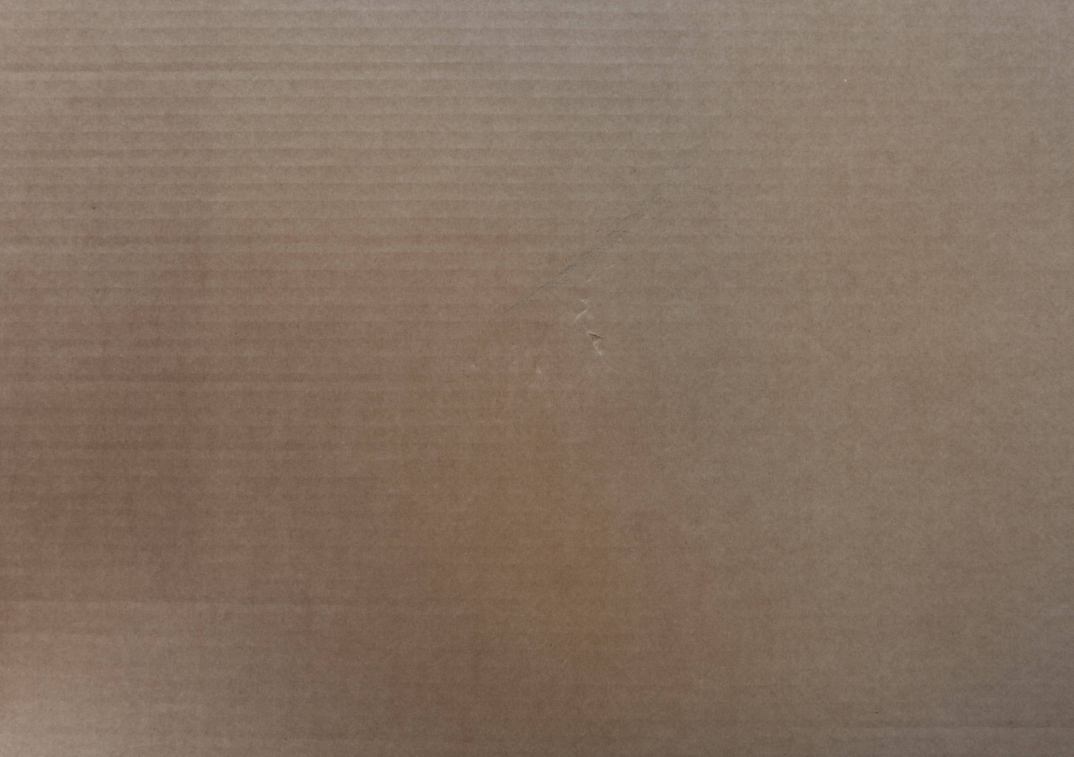 Boxing 桌布 壁紙 — 棕色瓦楞紙板表面的特寫，具有紋理、微妙的漸變和輕微的刮痕。