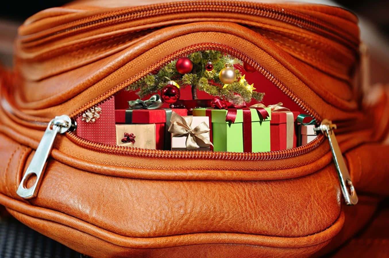 purse 桌布 壁紙 — 棕色皮革包包拉鍊的特寫，露出裡面色彩繽紛的聖誕禮物和一個迷你裝飾聖誕樹。