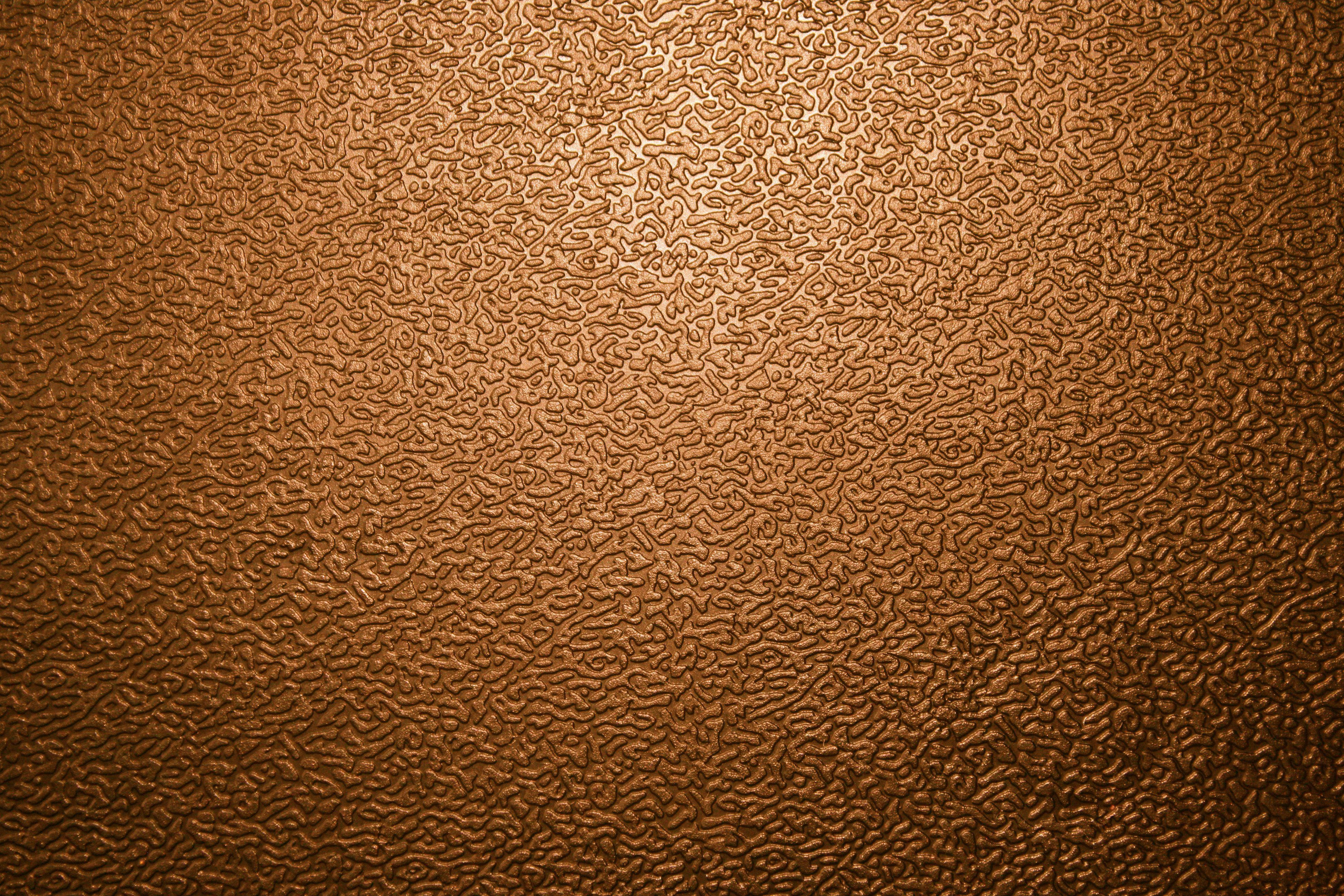 Textured 桌布 壁紙 — 棕色紋理表面的近距離特寫，帶有漩渦圖案，由上而下的溫暖光線照射。