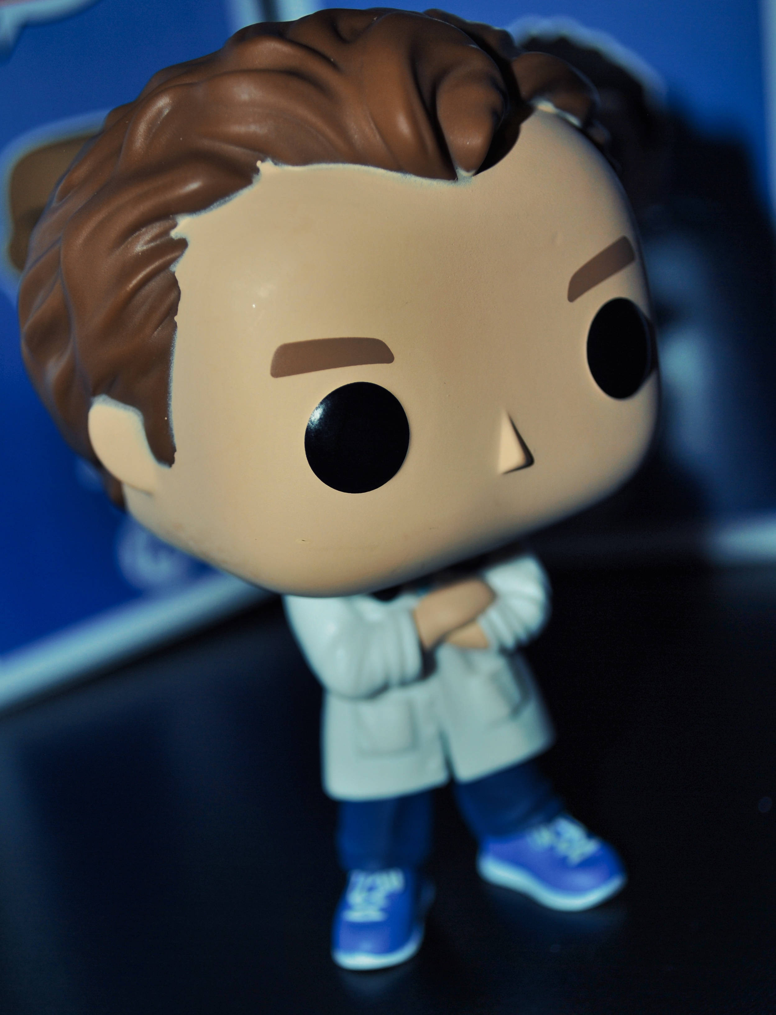 pop 桌布 壁紙 — 棕色頭髮、交叉雙臂的Funko Pop公仔特寫，站在藍色背景前。