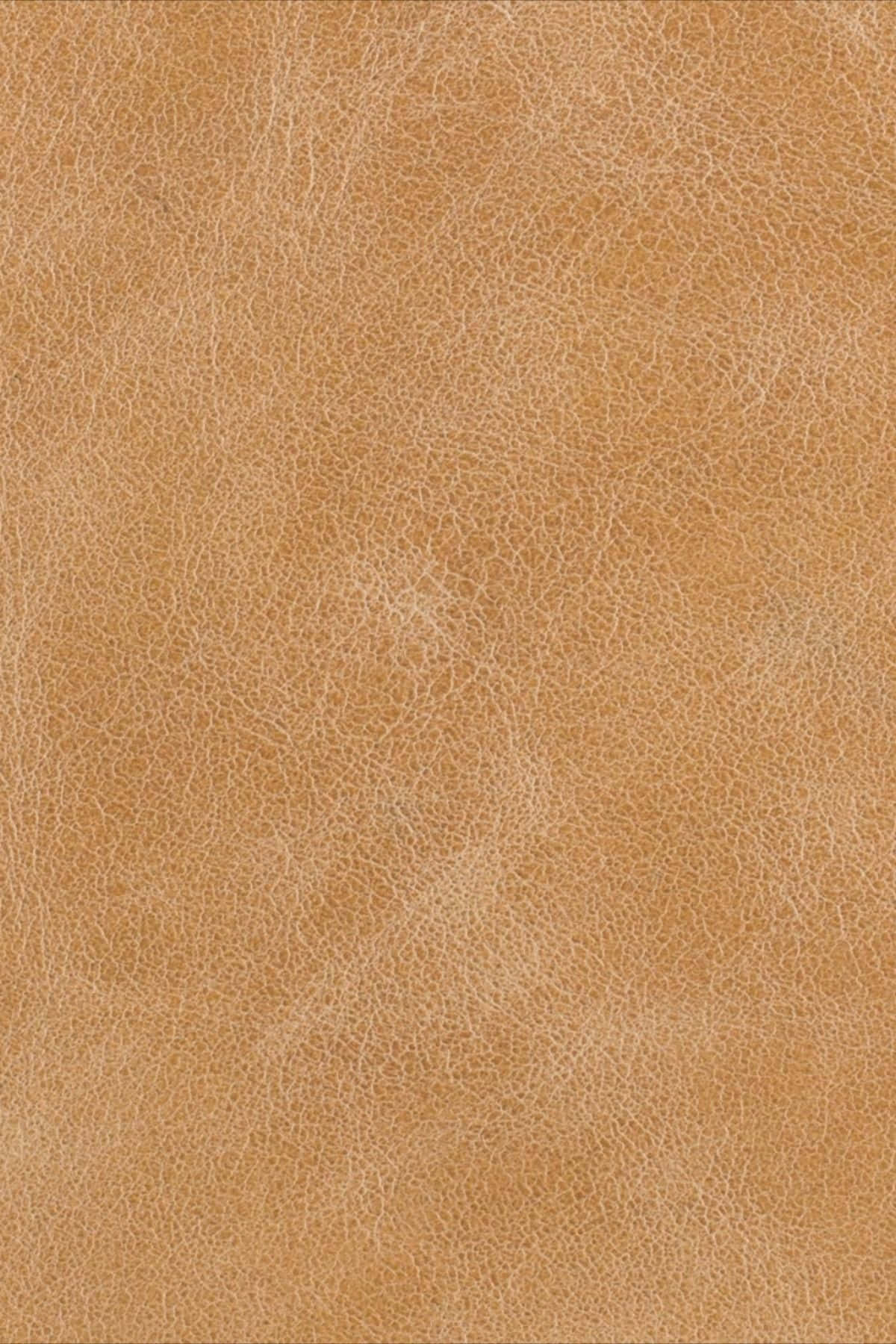 texture 桌布 壁紙 — 棕褐色皮革特寫，具有天然紋理和柔和光線下的細微皺褶。