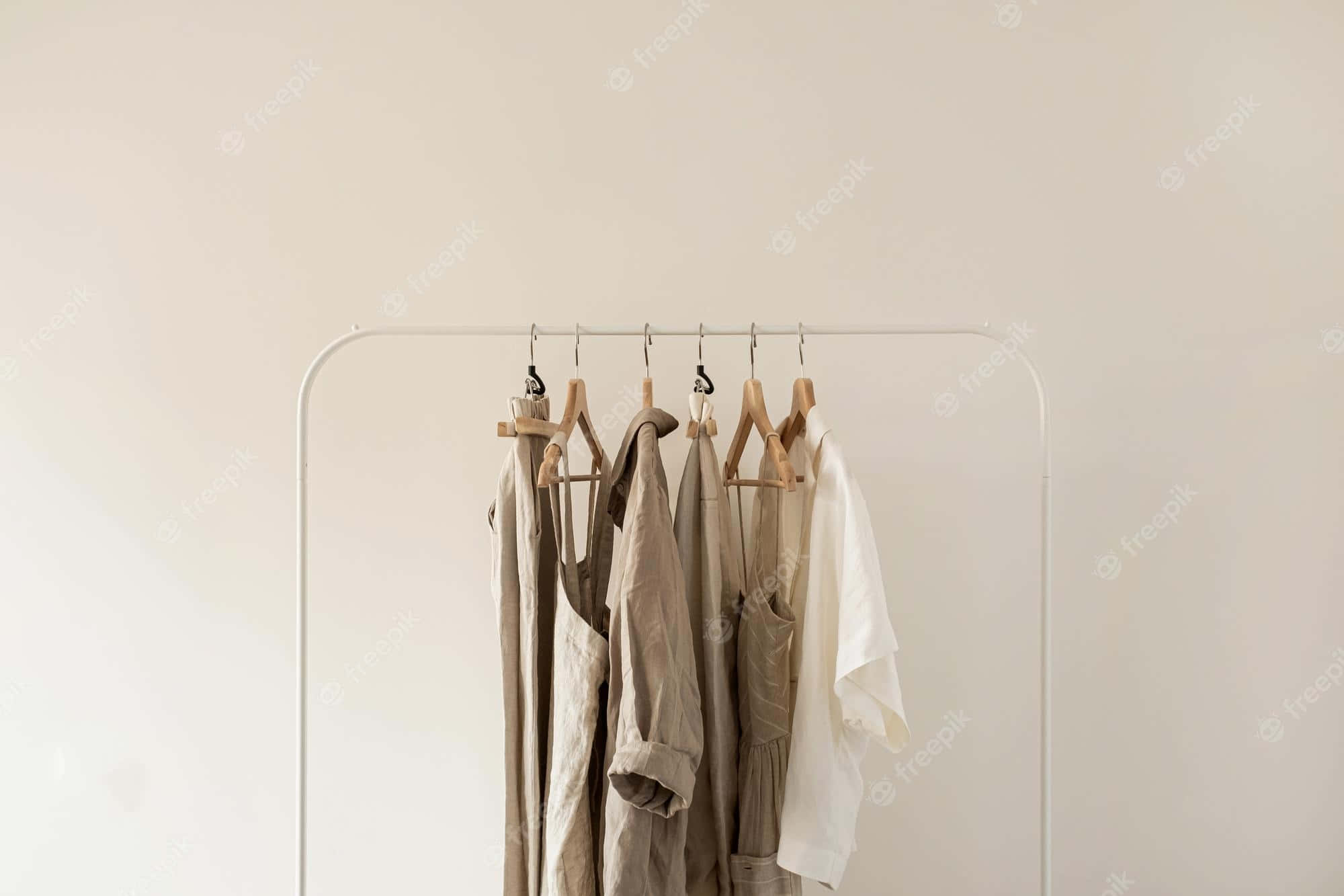 Clothes 桌布 壁紙 — 極簡主義衣架，掛著中性色調衣物，背景為純米白色牆壁。