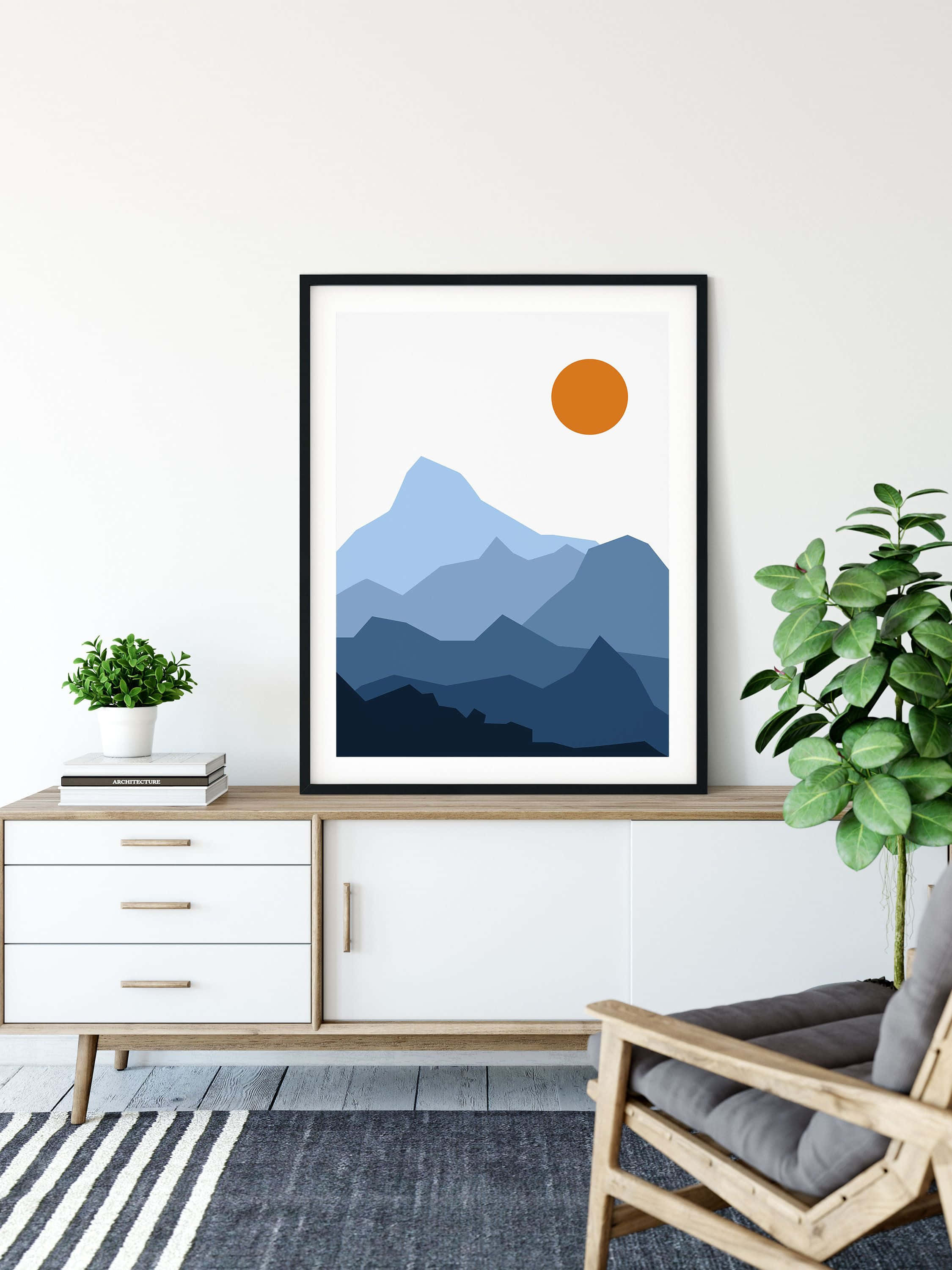 Modern Minimalist Art 桌布 壁紙 — 極簡山脈藝術印刷品，帶有層疊藍色山峰和橙色太陽，懸掛在舒適客廳的現代木質控制台上方。