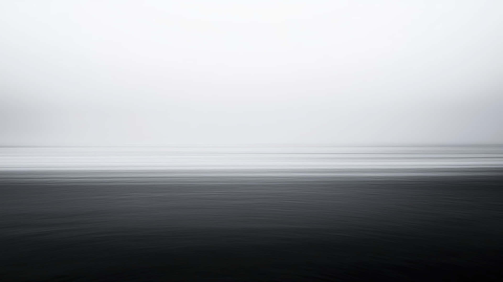 Minimalist Black and White Ocean Horizon with Soft Gradient Tones and Calm Water 壁紙 — 極簡海景，以鮮明的地平線將黑暗起伏的海面與蒼白陰沉天空分隔開來。