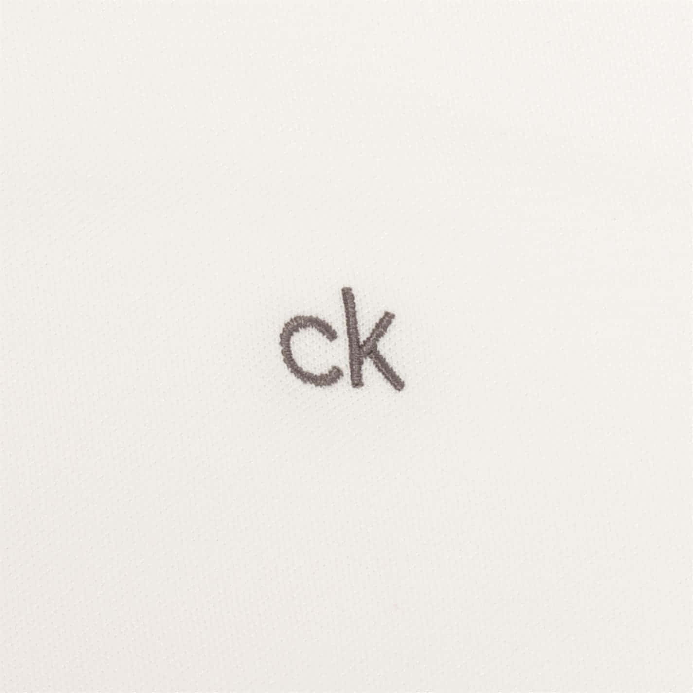 Calvin Klein 桌布 壁紙 — 極簡特寫：灰色刺繡ck標誌在質感白色布料表面。