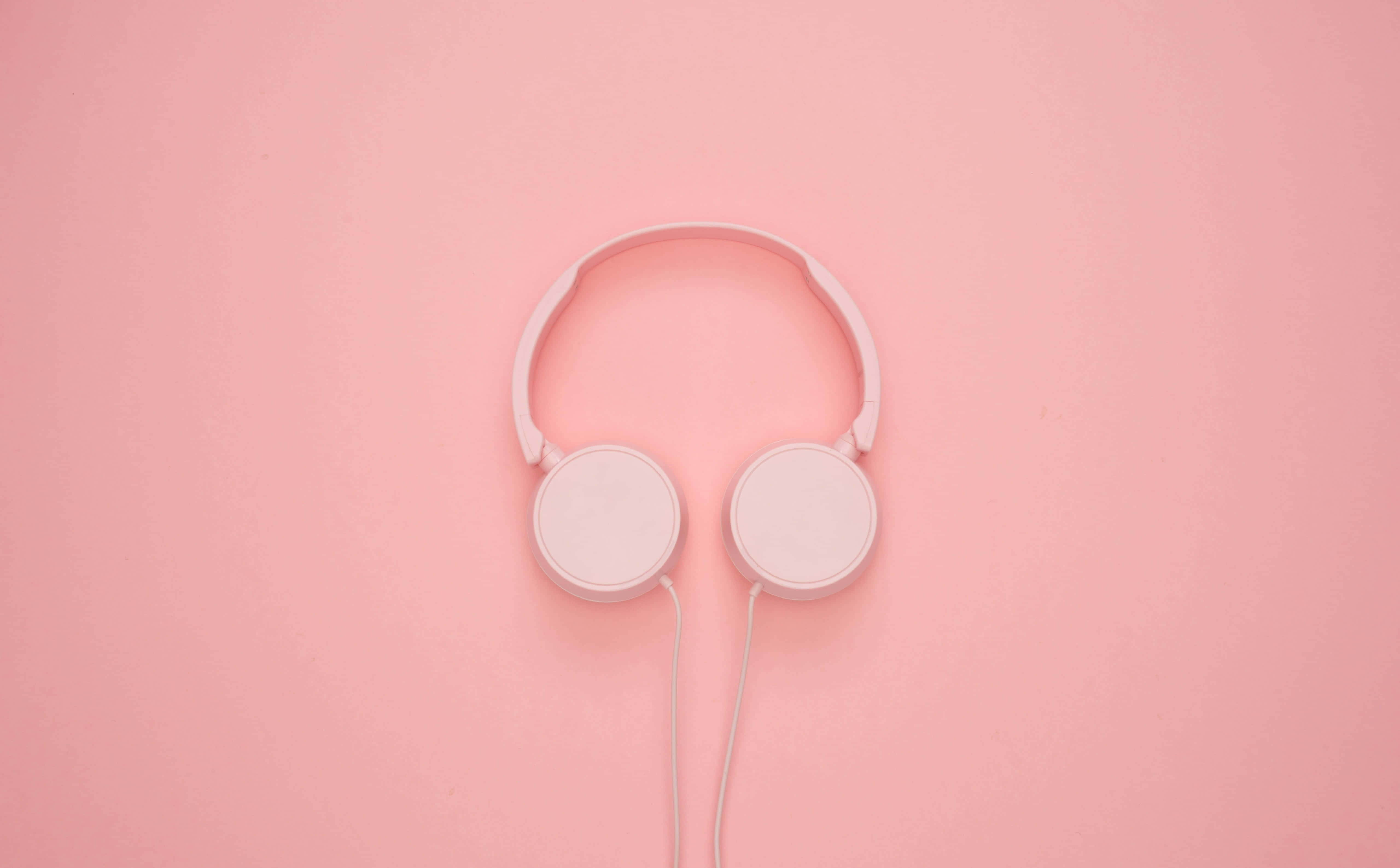 Aesthetic Music 桌布 壁紙 — 極簡粉色頭戴式耳機居中放置在純色粉彩粉紅背景上，線條簡潔，光線柔和。