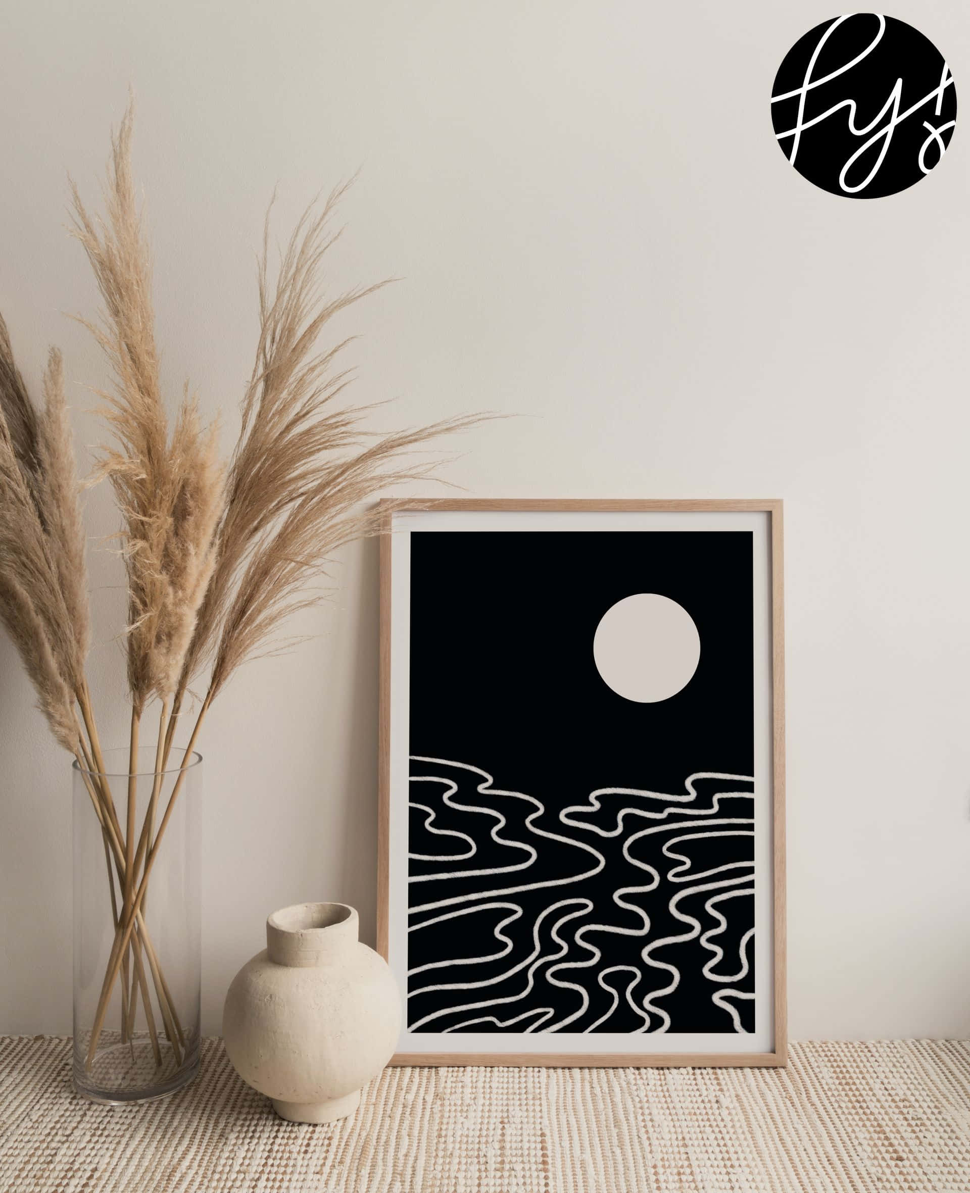 Modern Minimalist Art 桌布 壁紙 — 極簡黑白框畫，帶有月亮和波浪線條，放在編織地毯上，旁邊有乾燥蒲葦和陶瓷裝飾。