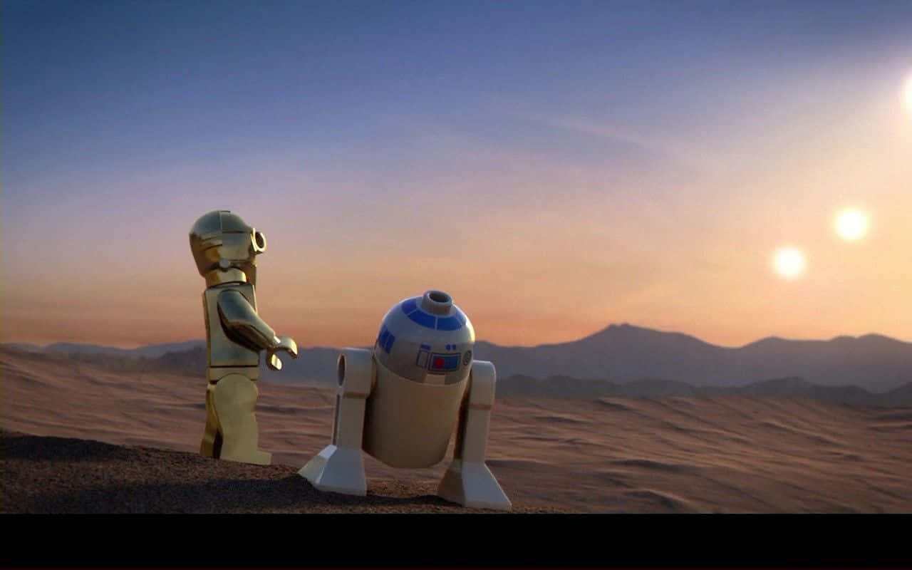 酷炫星際大戰 桌布 壁紙 — 樂高C-3PO和R2-D2站在沙漠星球上，夕陽西下，天空中有兩個太陽發光。