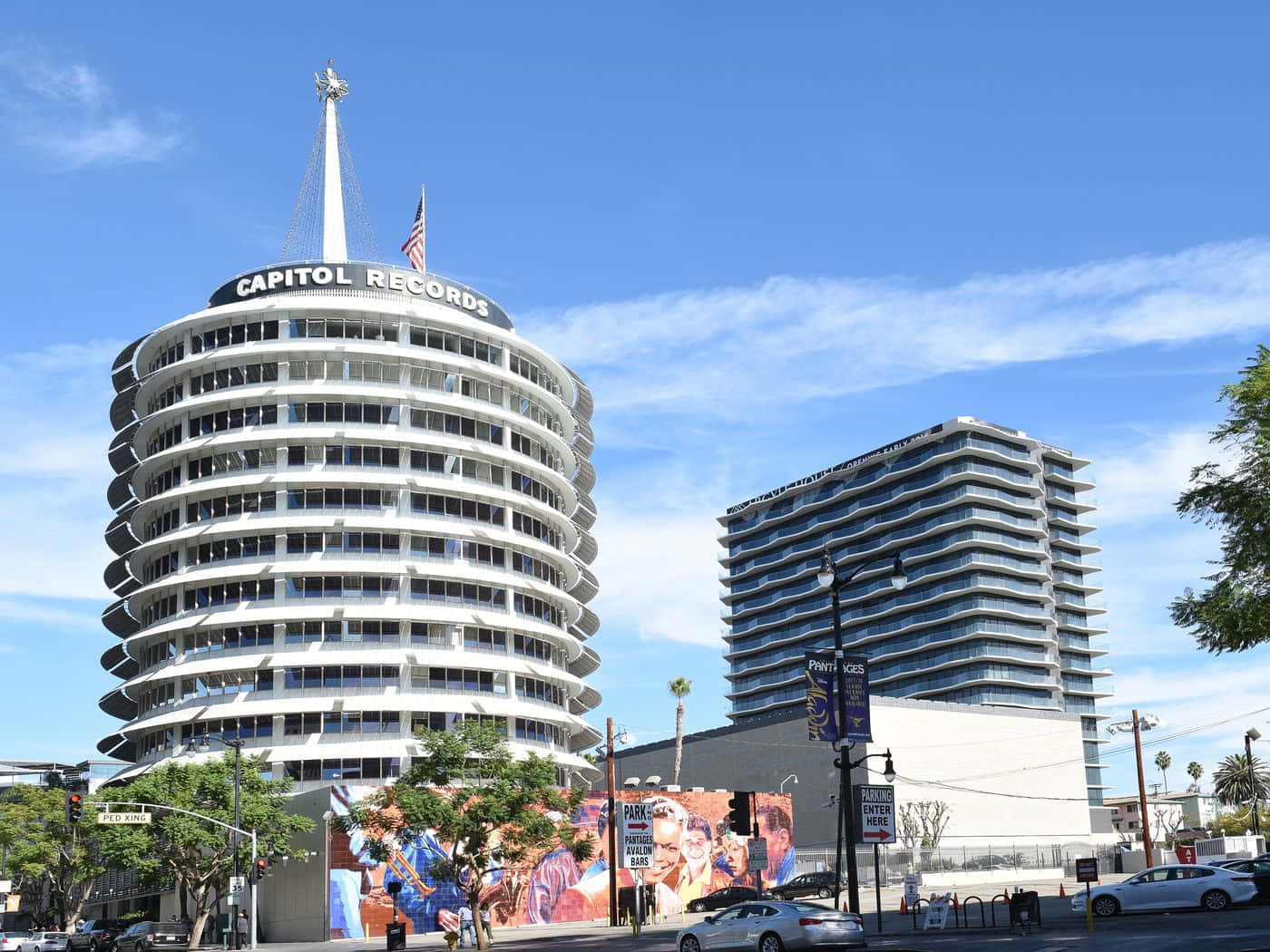 Sunny Day 桌布 壁紙 — 標誌性的 Capitol Records 大樓在明亮的藍天和縷縷白雲下高聳矗立，其圓形白色結構和尖塔主導了城市景觀。