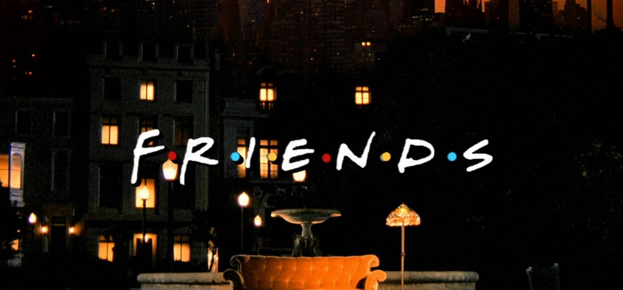 Friends Logo 桌布 壁紙 — 標誌性的《六人行》標誌在夜間城市景觀中發光，窗戶溫暖明亮，屋頂上有一張沙發。