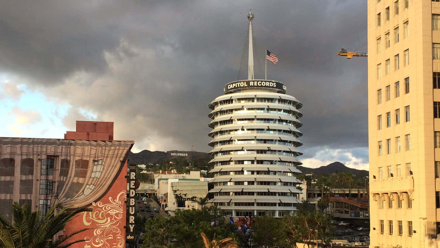 Buildings 桌布 壁紙 — 標誌性的Capitol Records大樓在戲劇性的暴風雲下高聳，背景是荷里活山丘。