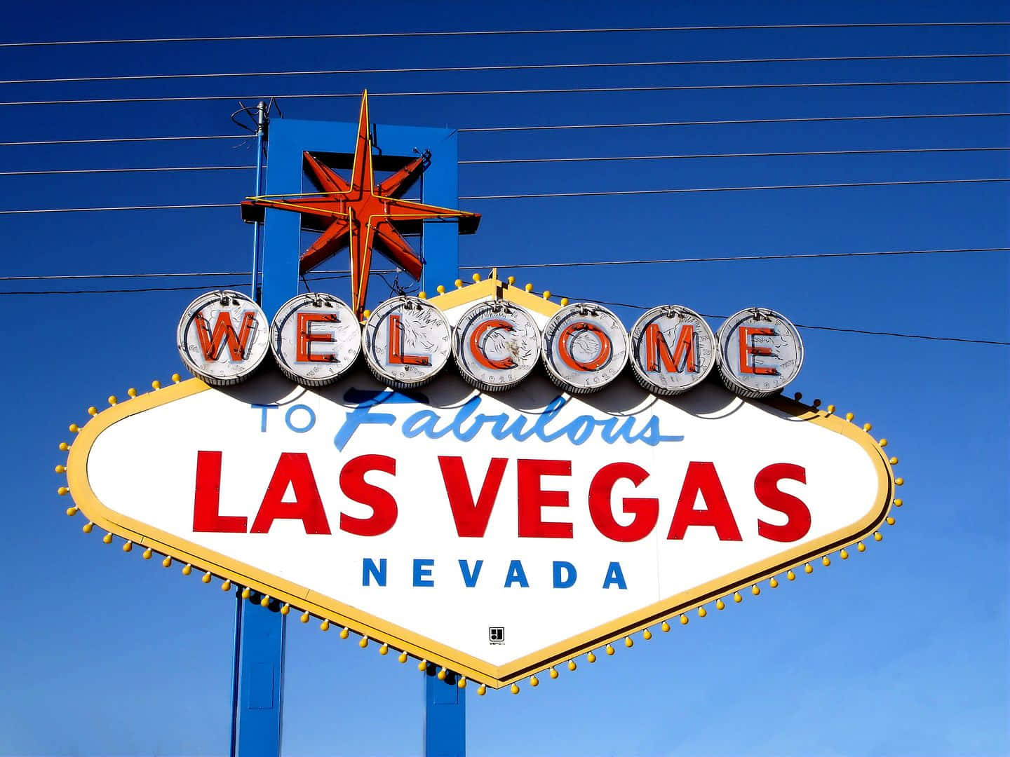 拉斯維加斯 桌布 壁紙 — 標誌性的Welcome to Fabulous Las Vegas招牌在晴朗的藍天下發光，上方有電線交叉。