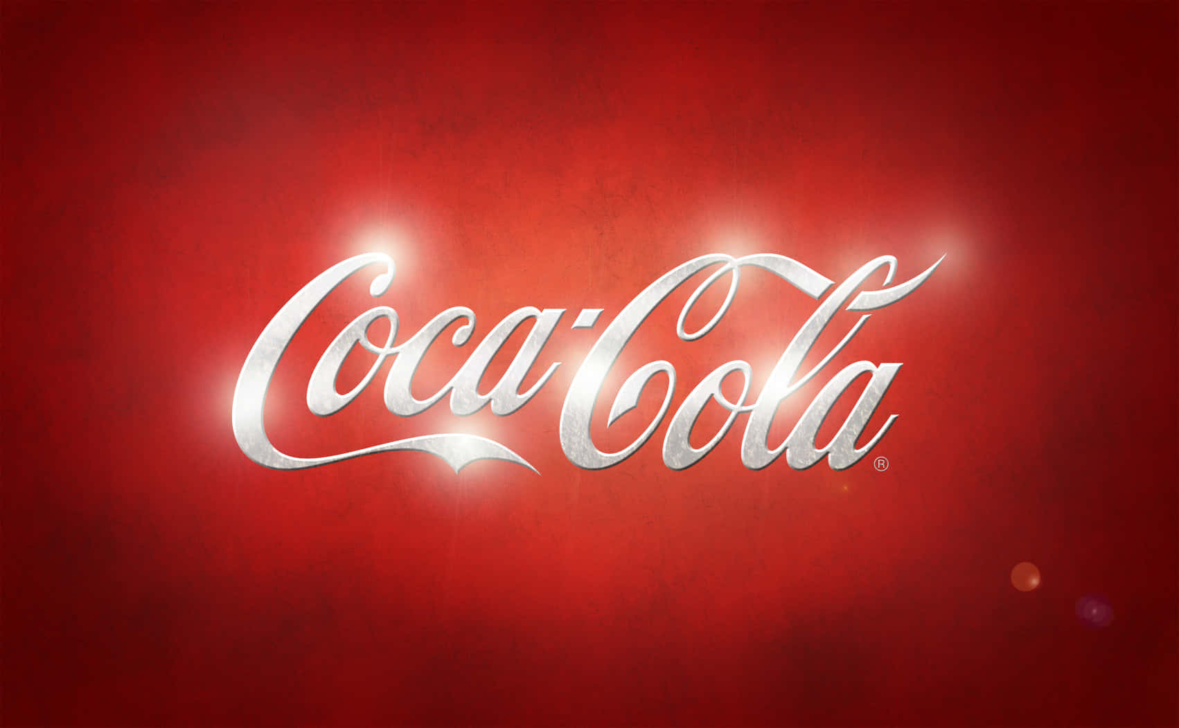 Coca Cola Logo 桌布 壁紙 — 標誌性的可口可樂標誌在豐富紋理的紅色背景上閃耀著銀色光芒，帶有柔和鏡頭光暈。